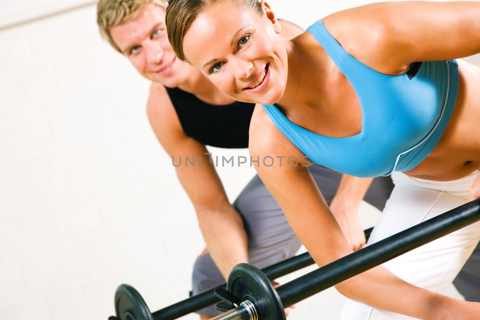 Very attractive and sportive couple doing power gymnastics with barbells