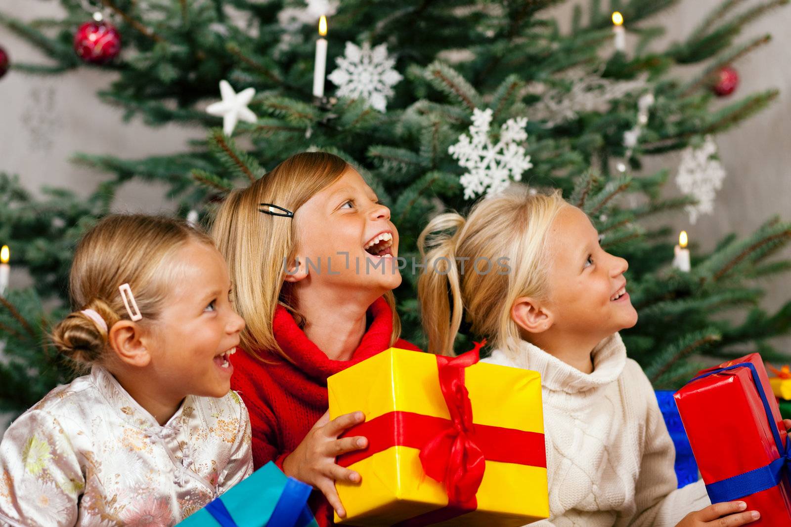 Family Christmas - three children having received gifts showing them around