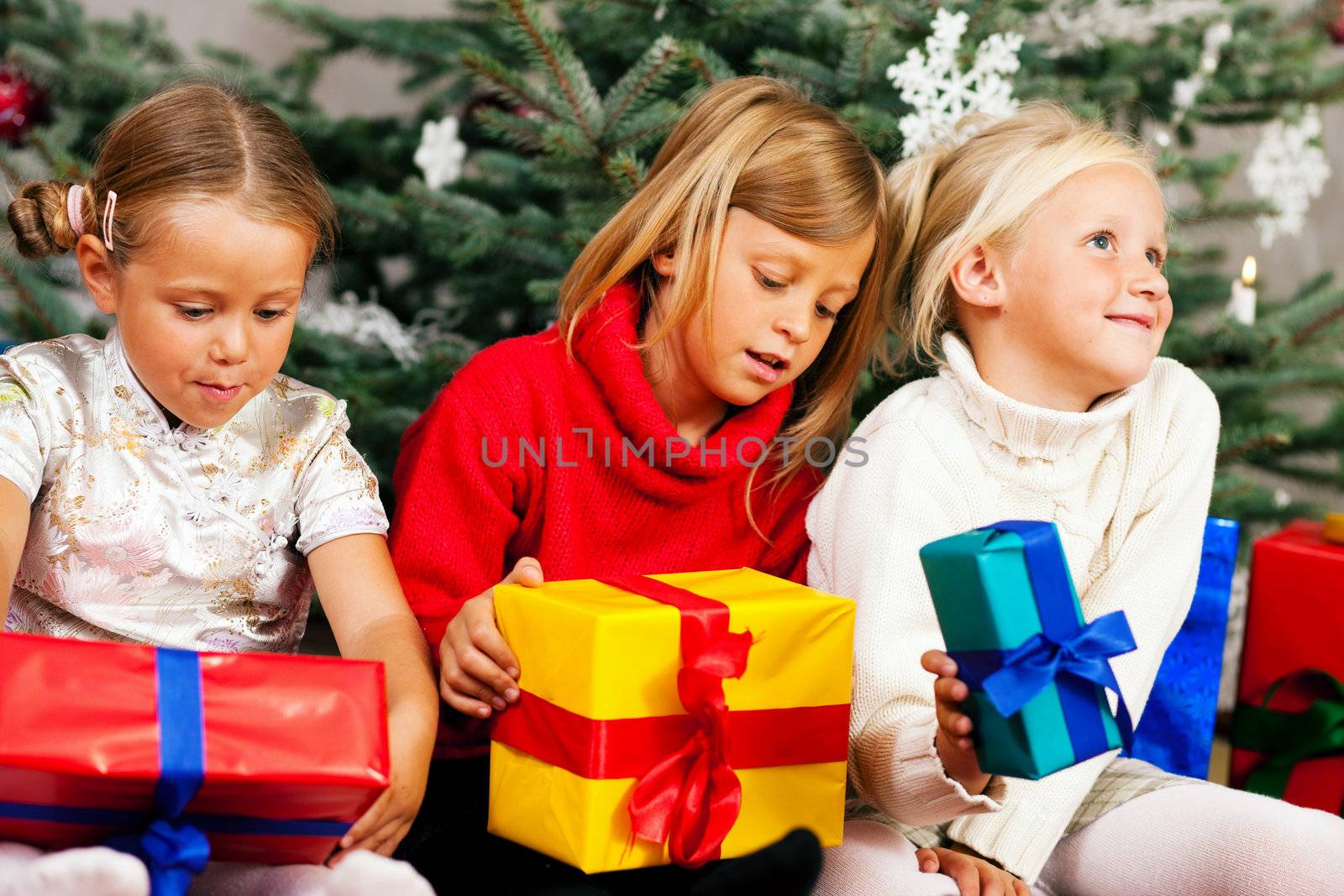 Family Christmas - three children having received gifts showing them around