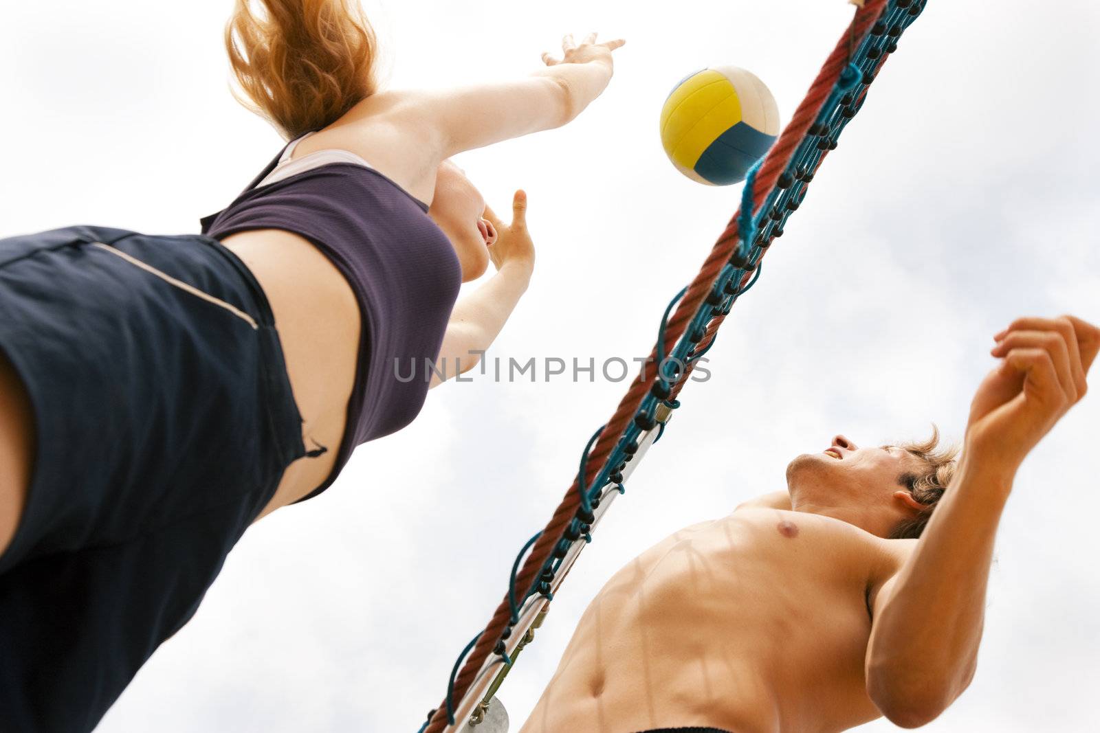 Players doing summer sports trying to block a dangerous attack in a beach volleyball game