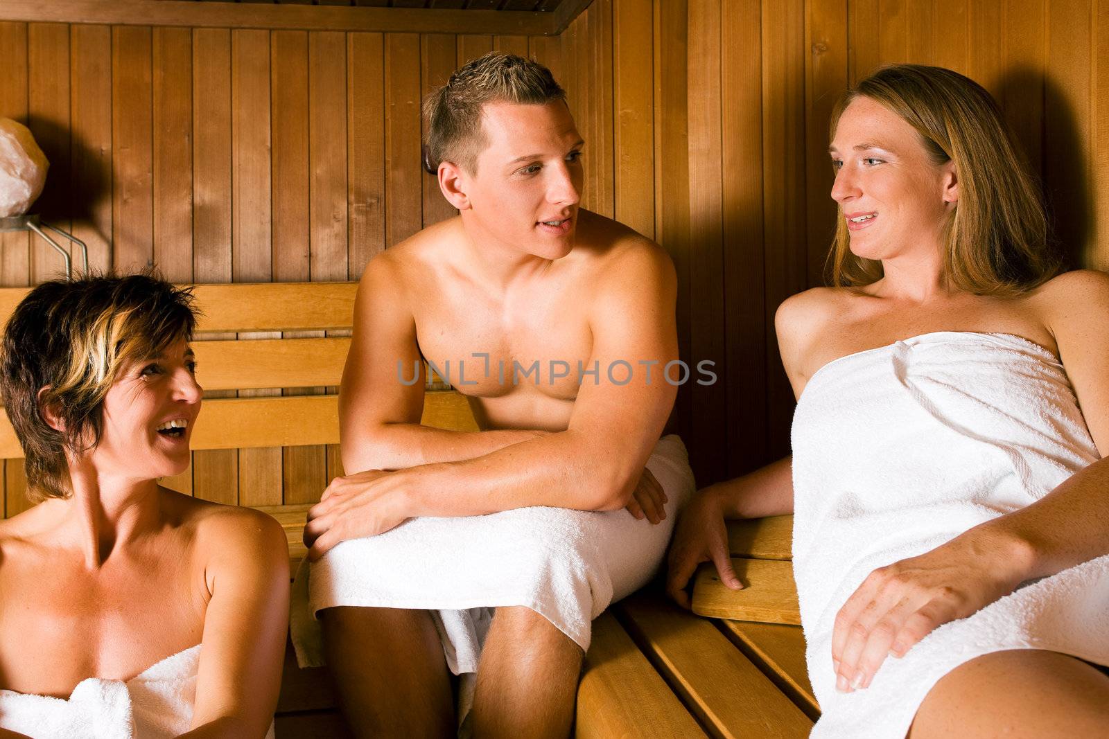 Three people (one male, two female) relaxing in a sauna, doing a lot for their health but also having fun with it