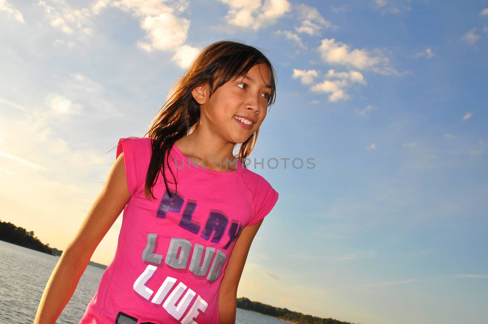 A smiling young girl during summer with sea and sky as background. Photo taken in the archipelago of Stockholm,Sweden.
