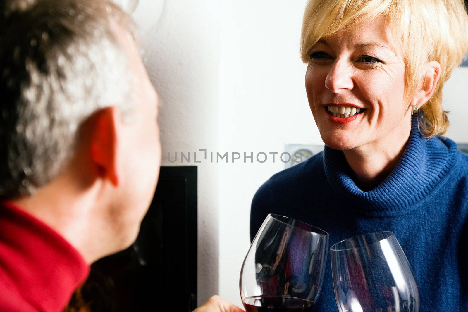 Mature couple having fun clinking glasses with red wine in a romantic setting