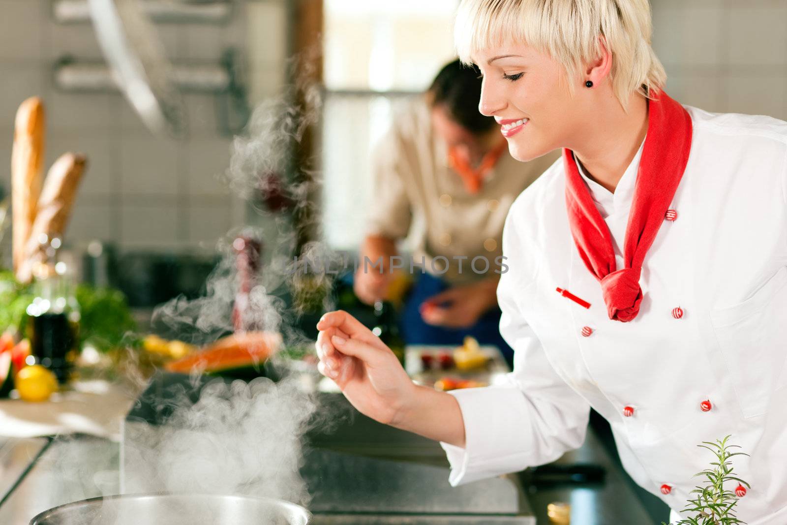 Two chefs in teamwork - man and woman - in a restaurant or hotel kitchen cooking delicious food