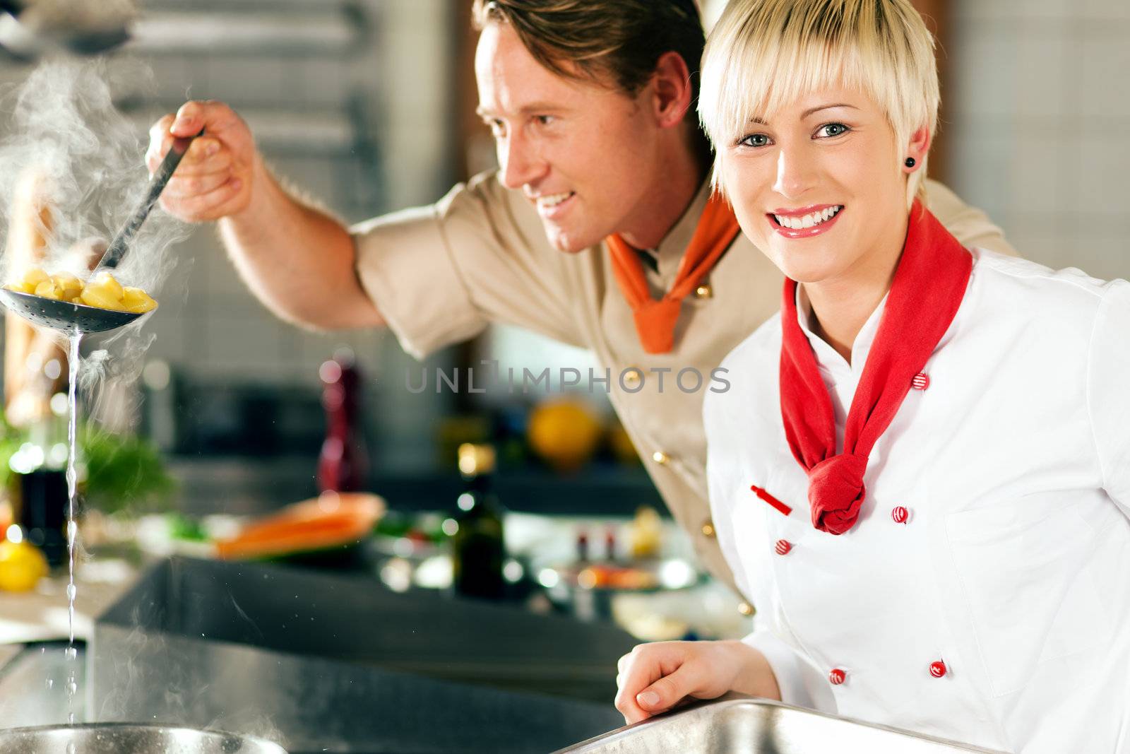 Chefs in a restaurant or hotel kitchen cooking by Kzenon