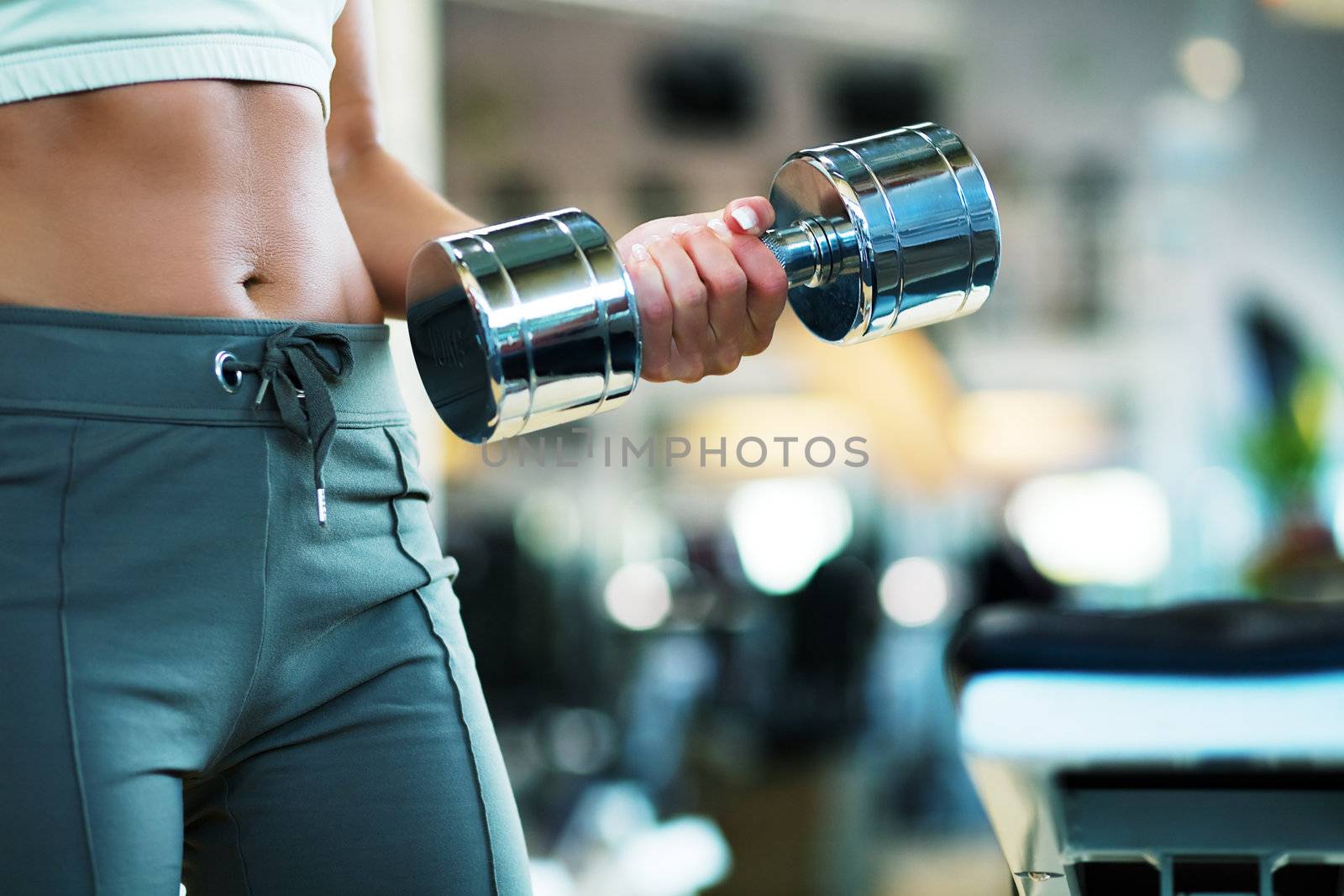 Woman (torso with beautiful belly) working out with dumb-bells