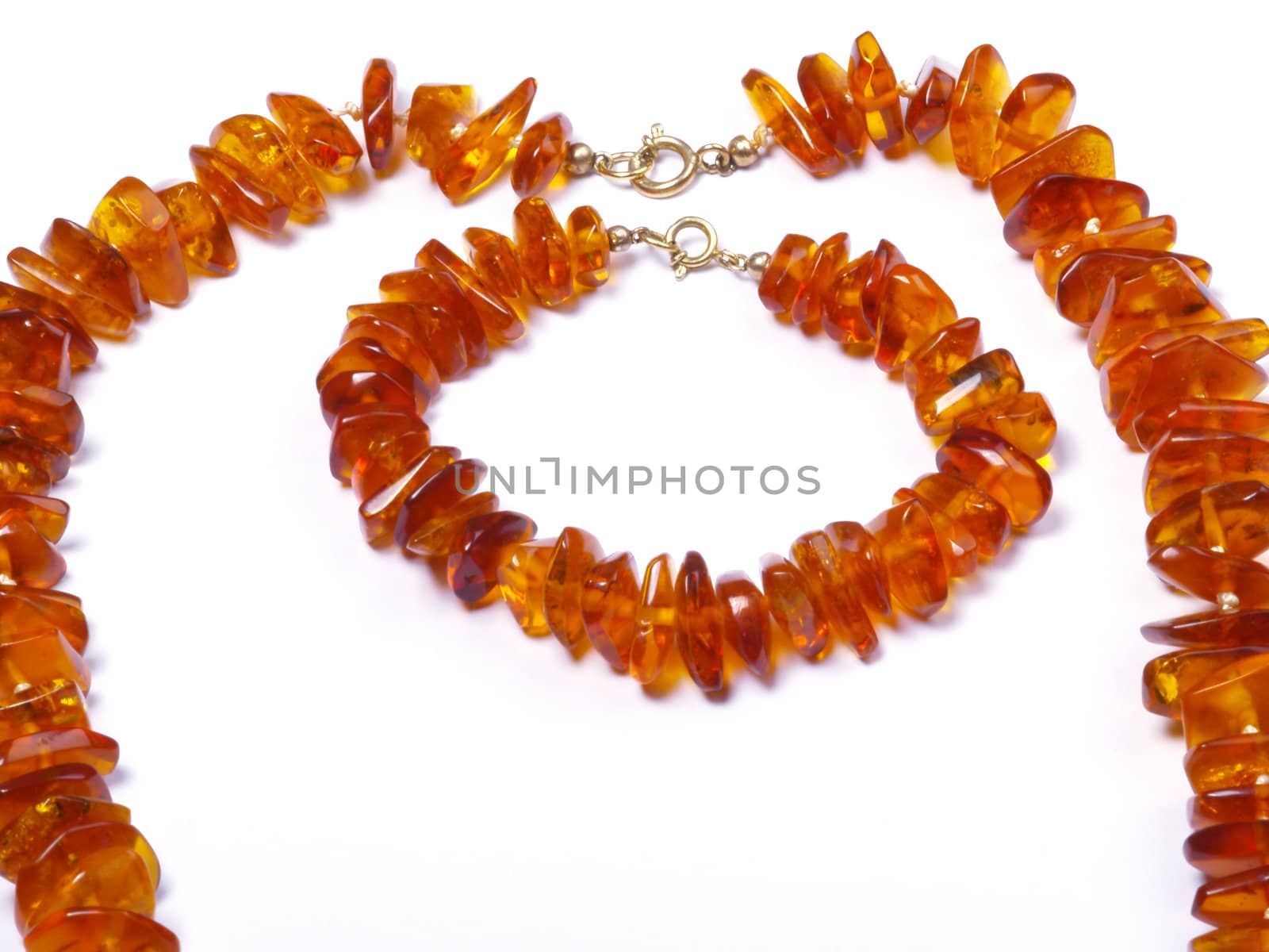 thread of amber bead and wristlet on off- white background close up