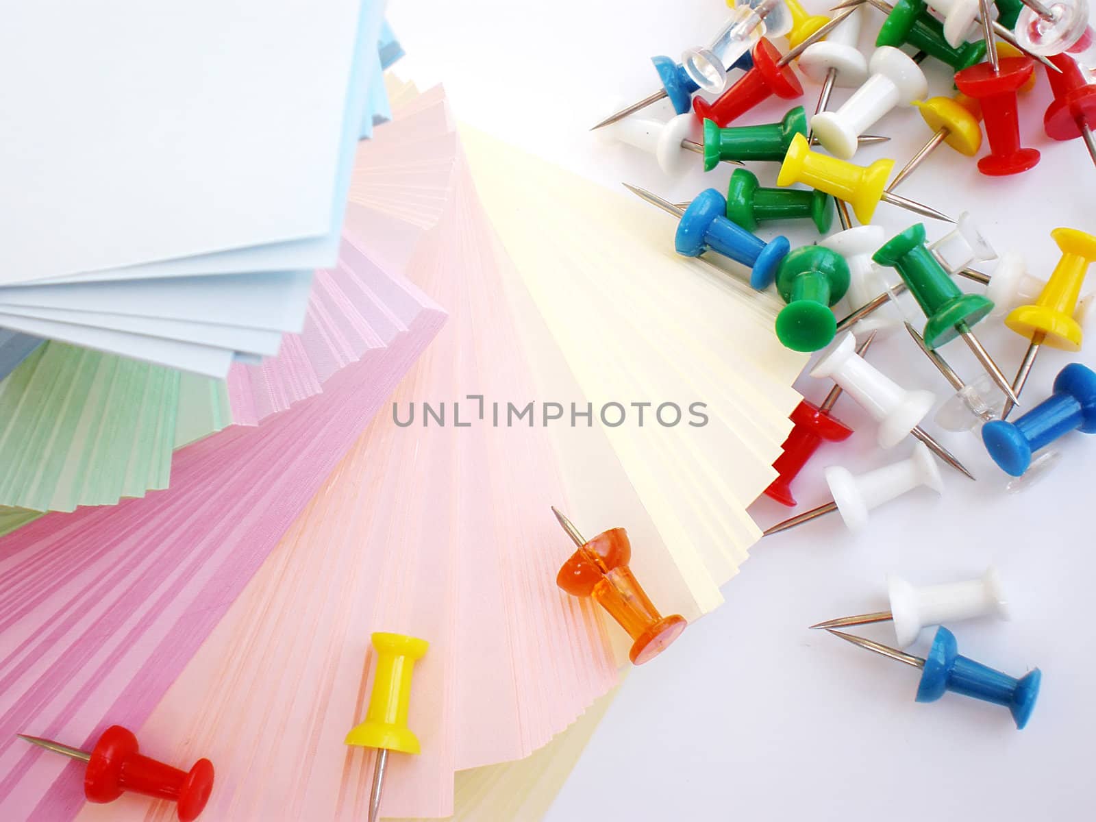 colorful sheets and push pins on white background