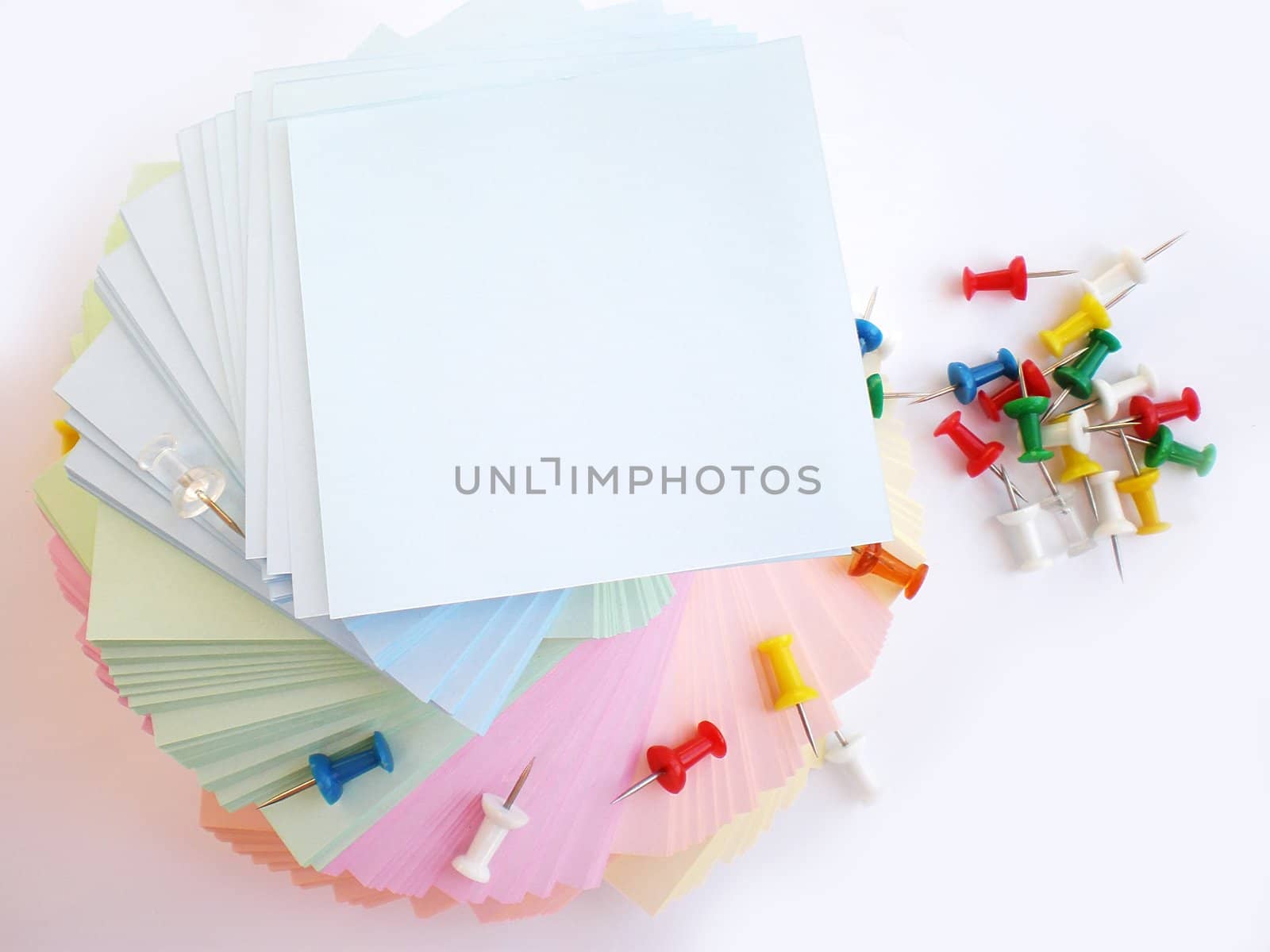 colorful sheets and push pins on white background