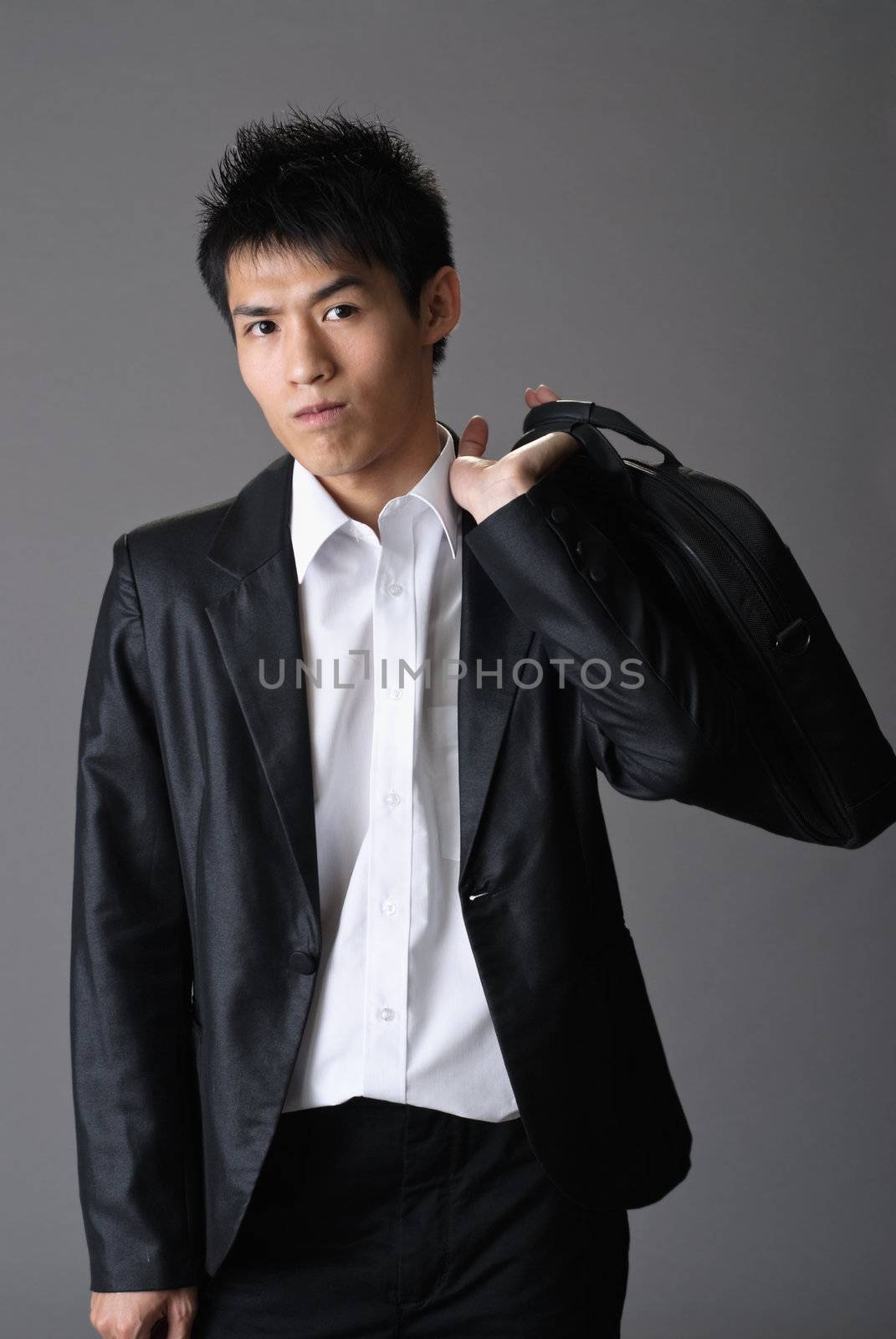 Handsome young businessman holding briefcase on shoulder.