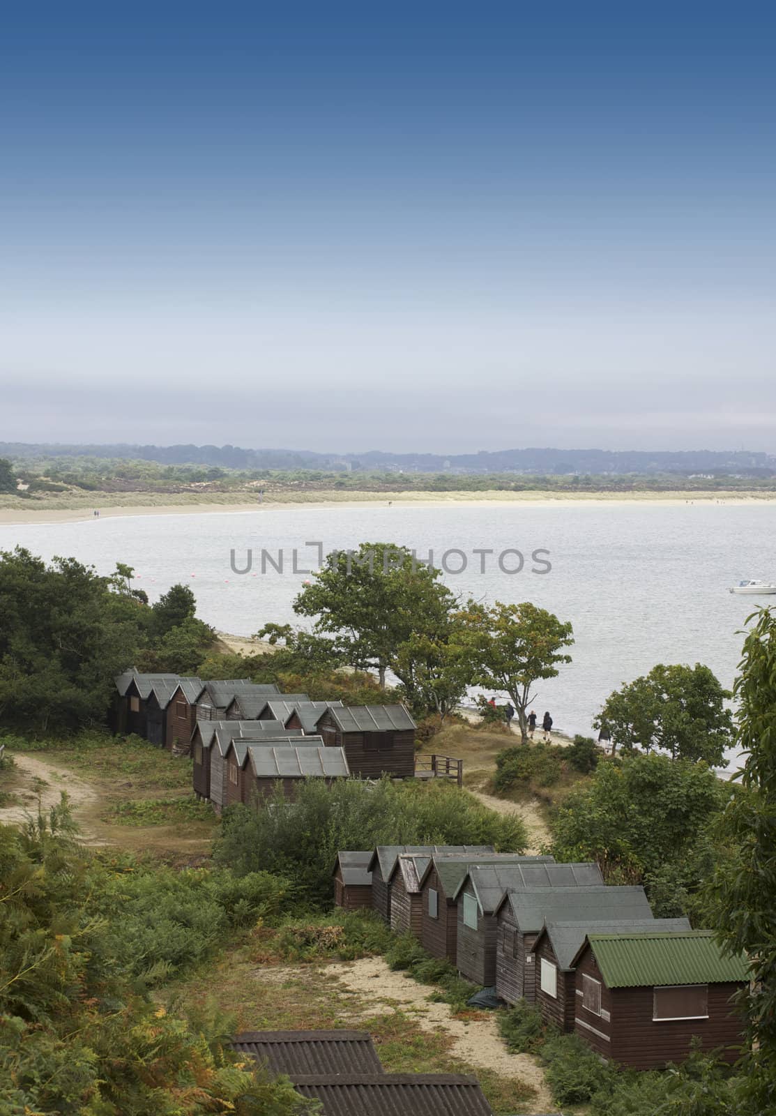 Wooden beach huts set amongst the sand dunes on Studland Beach in Dorset. View looking across the beach with the beach huts to the foreground.