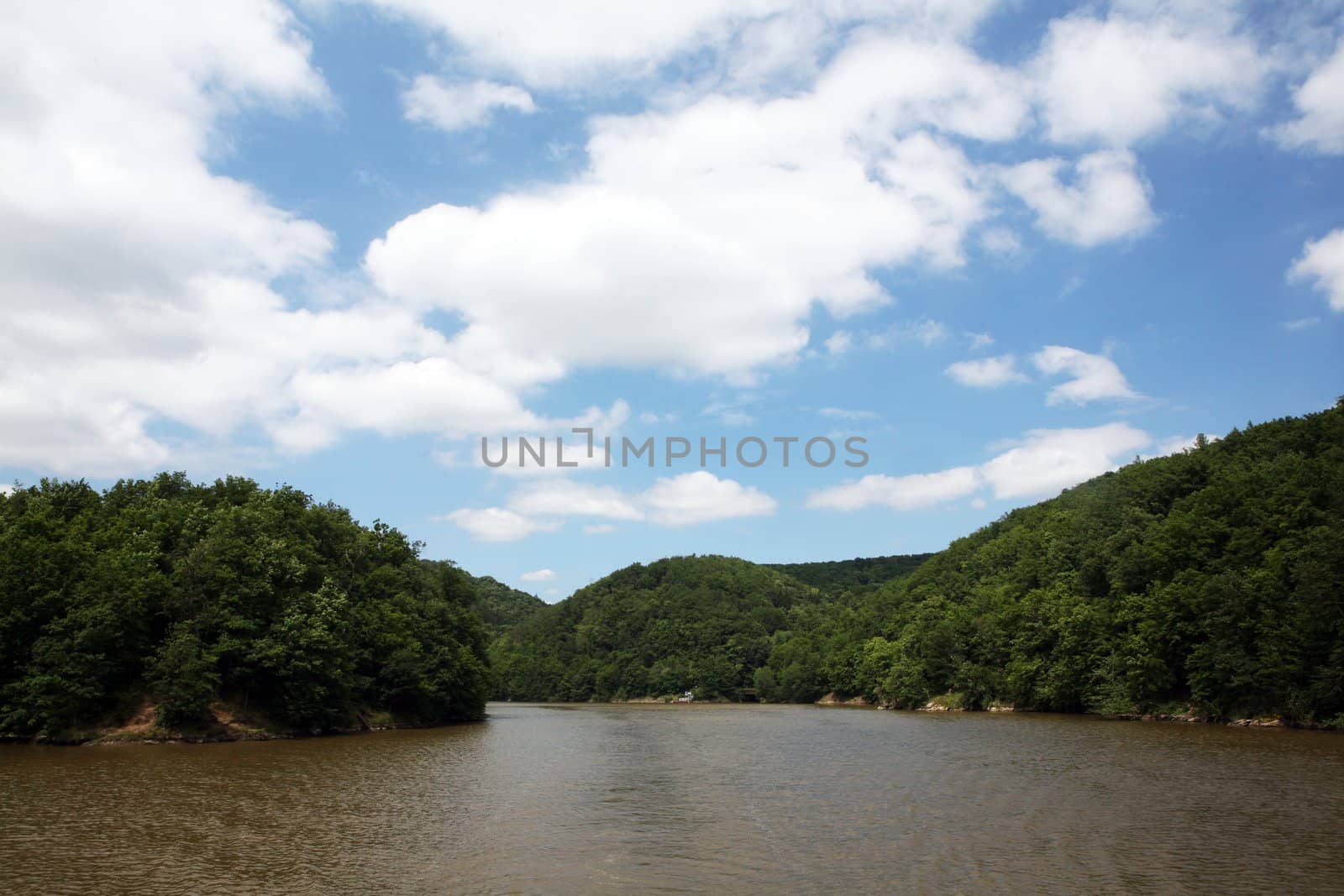 Beautiful blue cloudy sky and river with forest on the sides