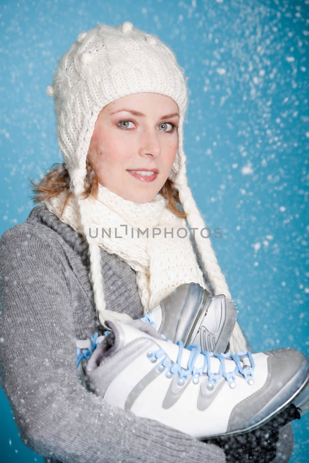 Pretty blond girl warmly dressed with her iceskates under her arm