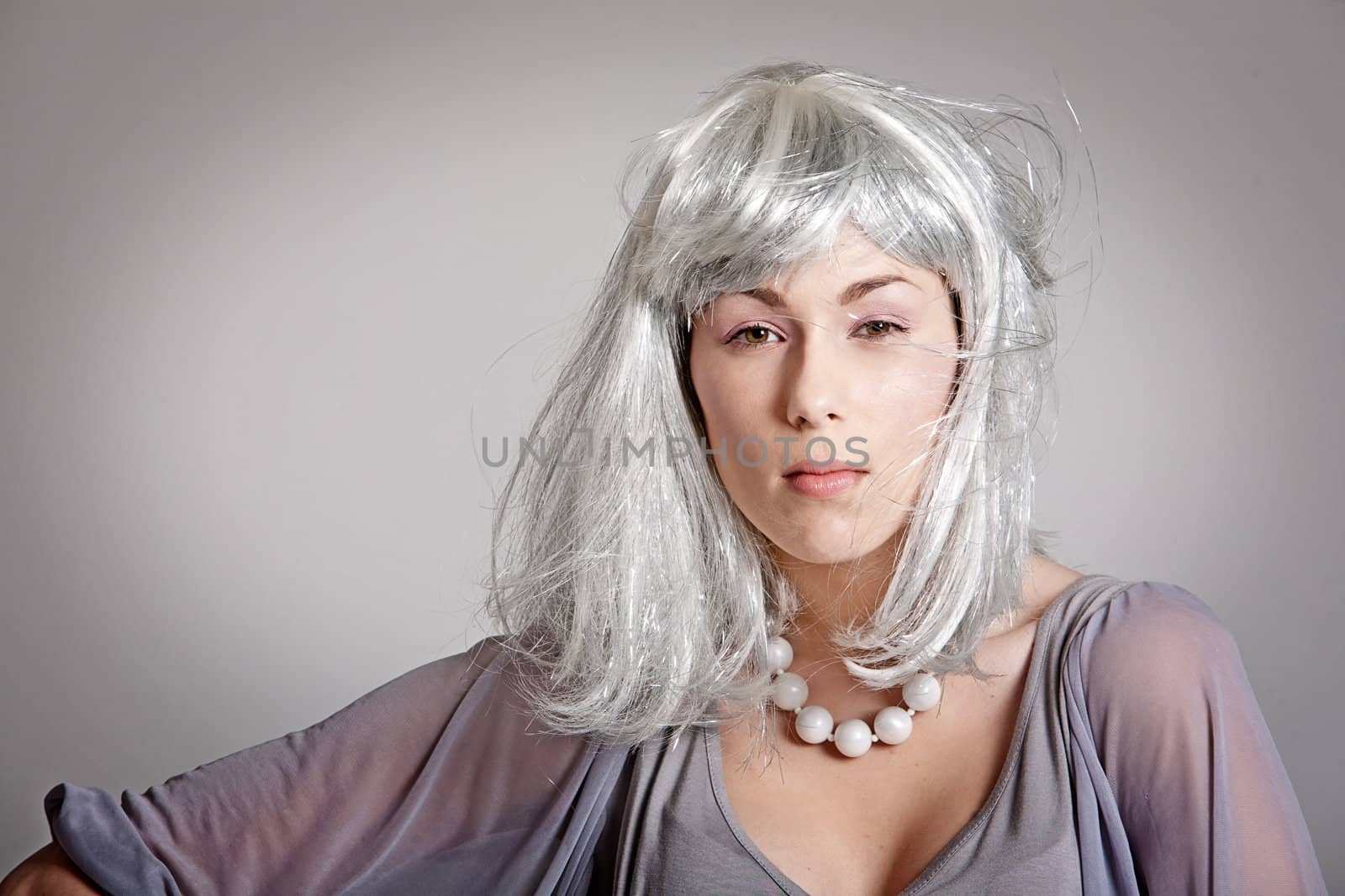 Beautiful woman with silvery wig on grey background