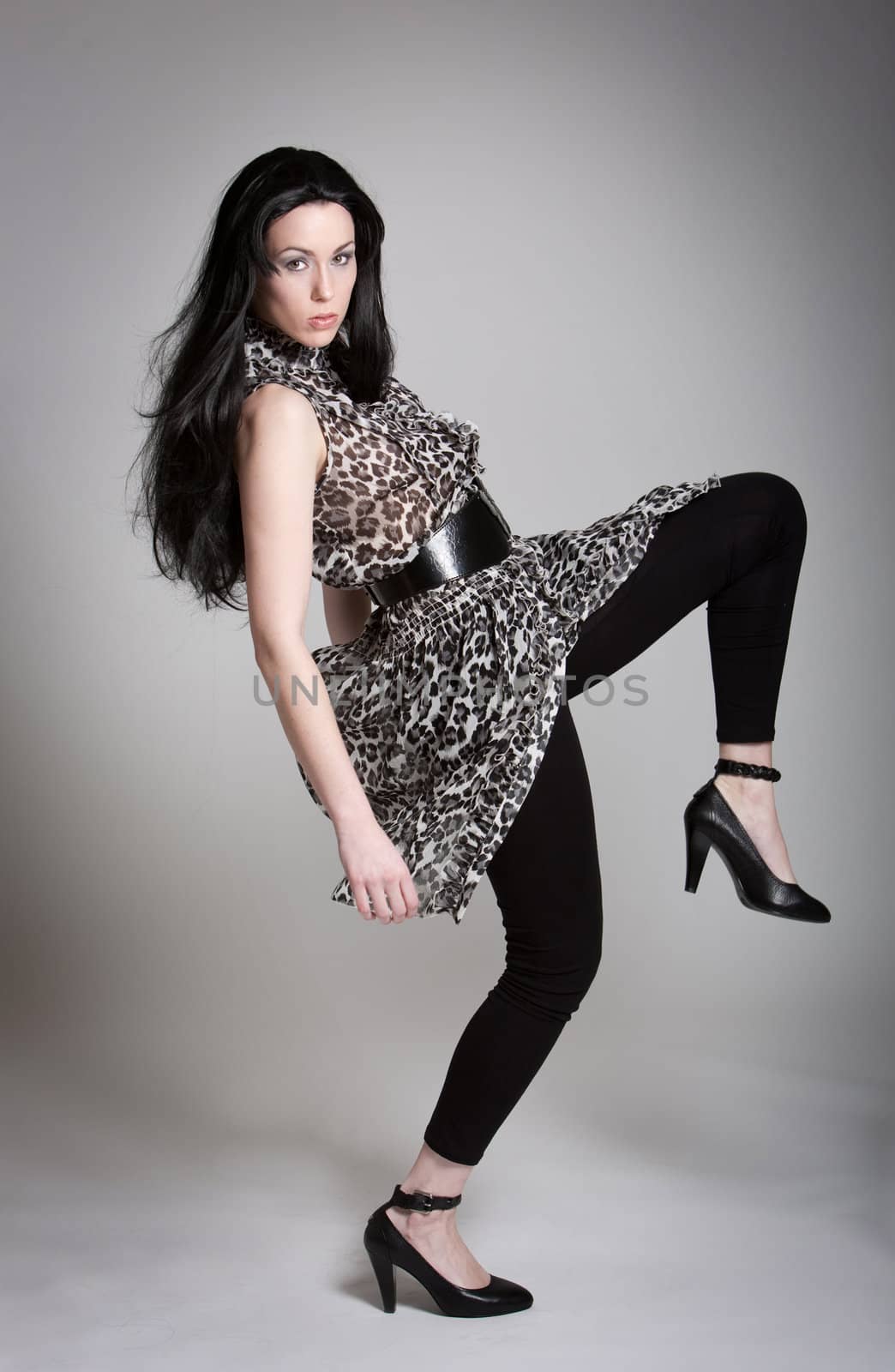 Beautiful black haired woman in fashionable outfit and high heels
