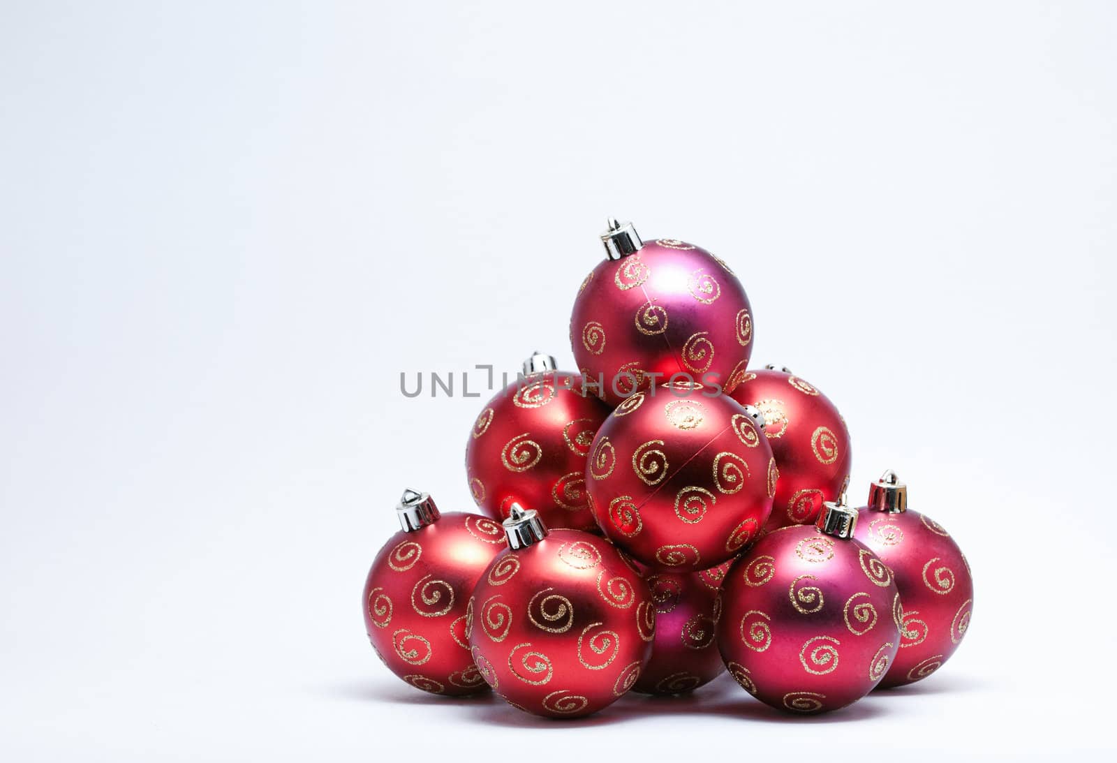 Pile of red Christmas Baubles with gold glitter on a white background. (Selective Focus)
