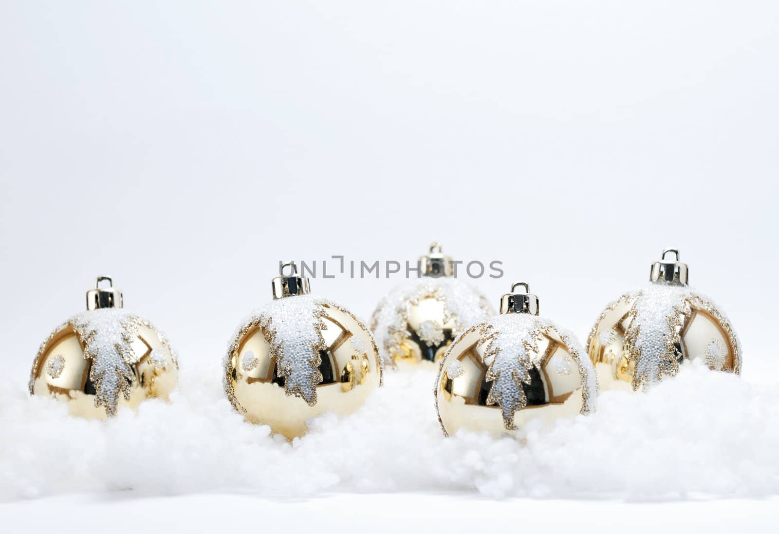 Gold Christmas Baubles (Selective Focus) with white glitter holly Leaf decoration on a white background.
