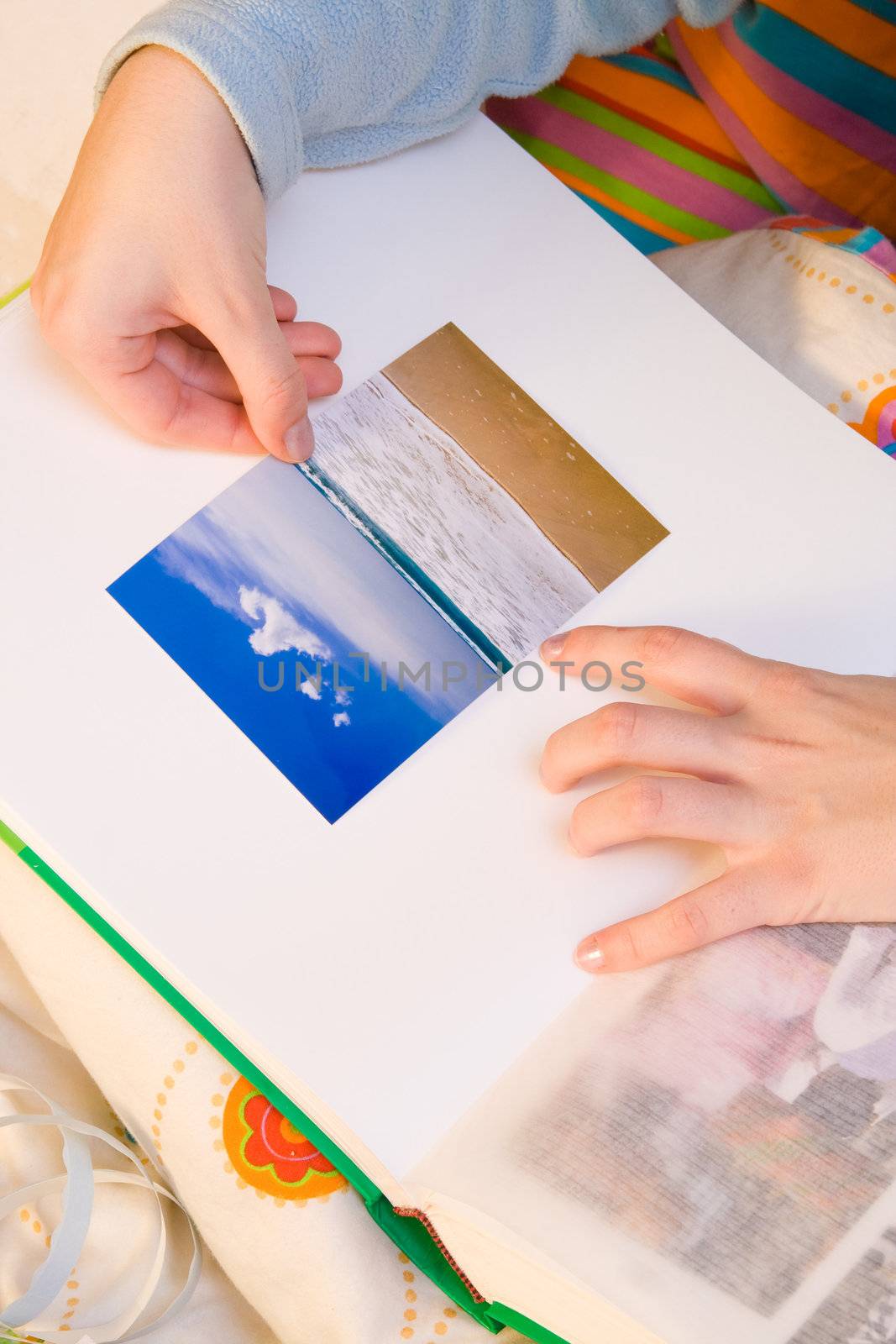 Woman hands sticking images in her photo album. Images can be replaced.