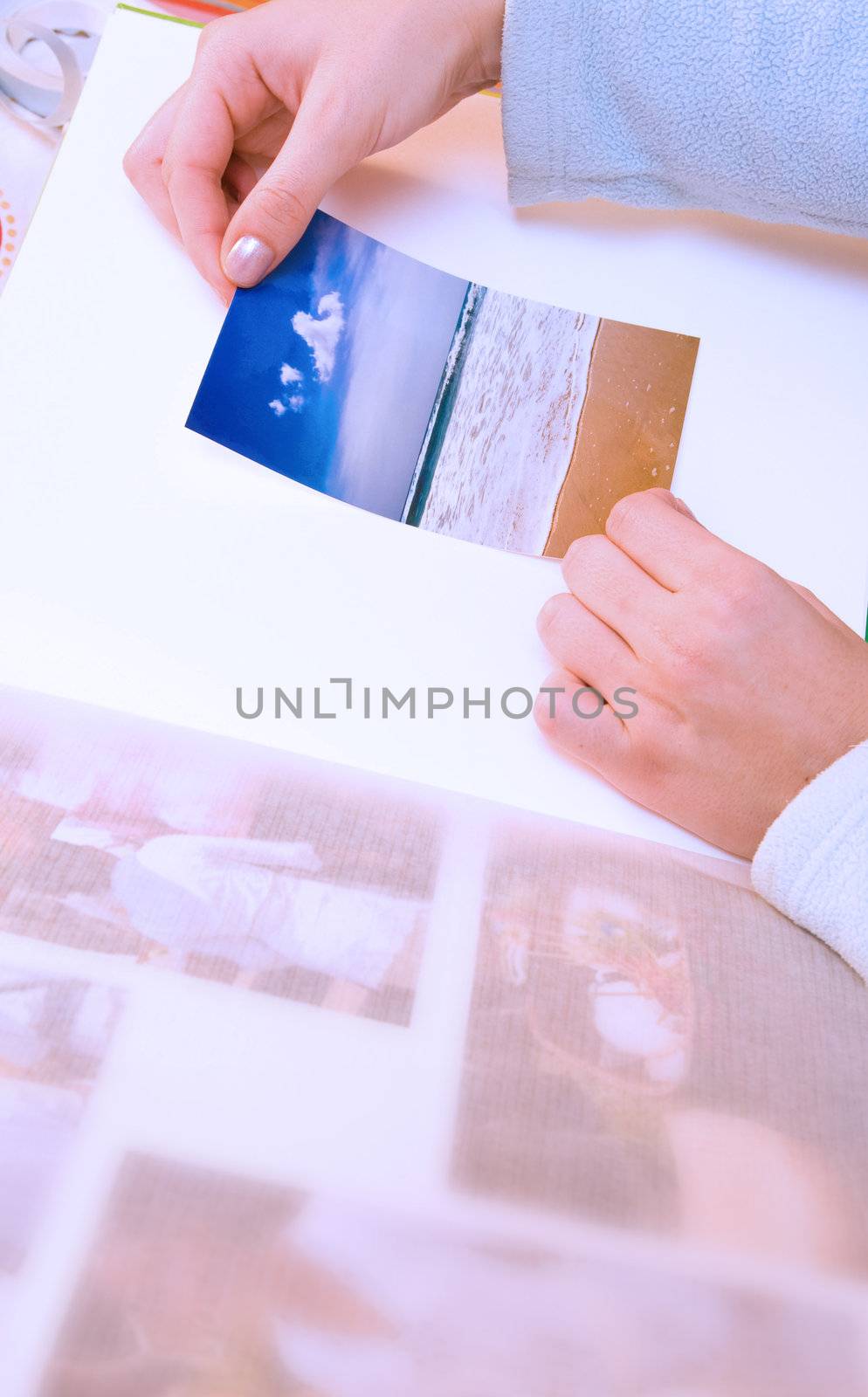 Woman hands sticking images in her photo album. Images can be replaced.