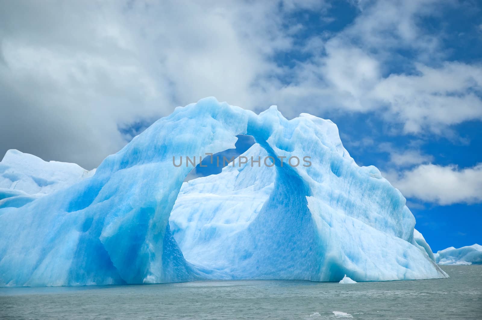 Iceberg floating in the water forming an arch.