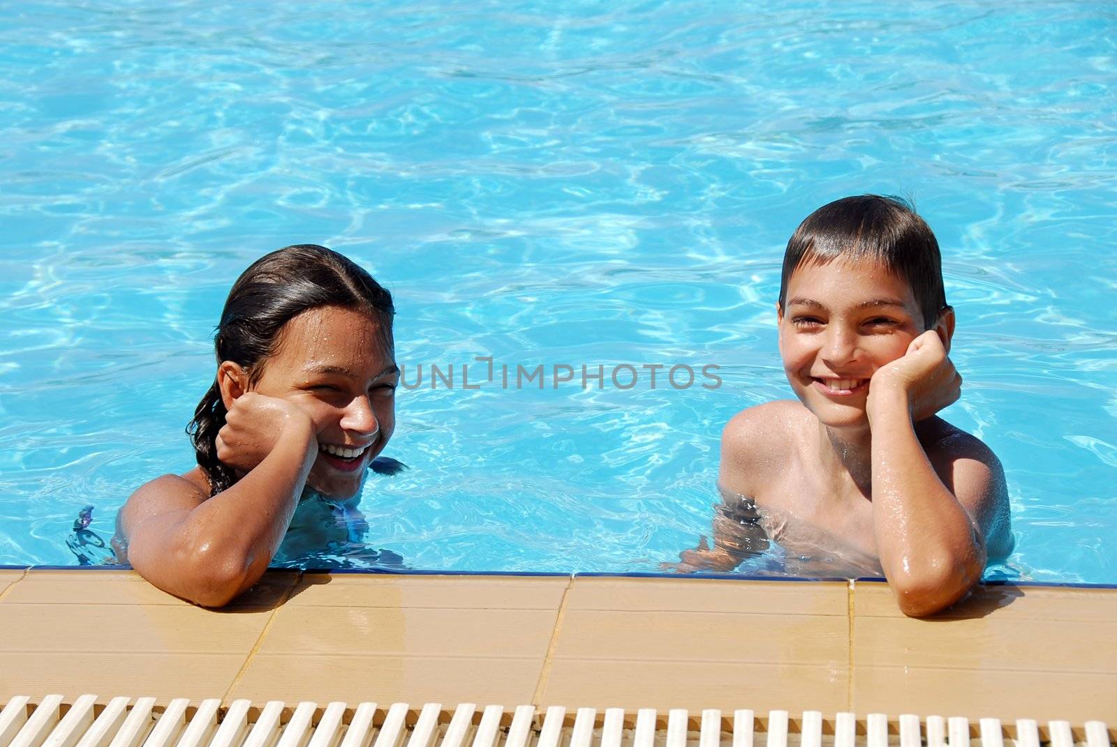 smiling girl and boy in blue swimming pool portrait