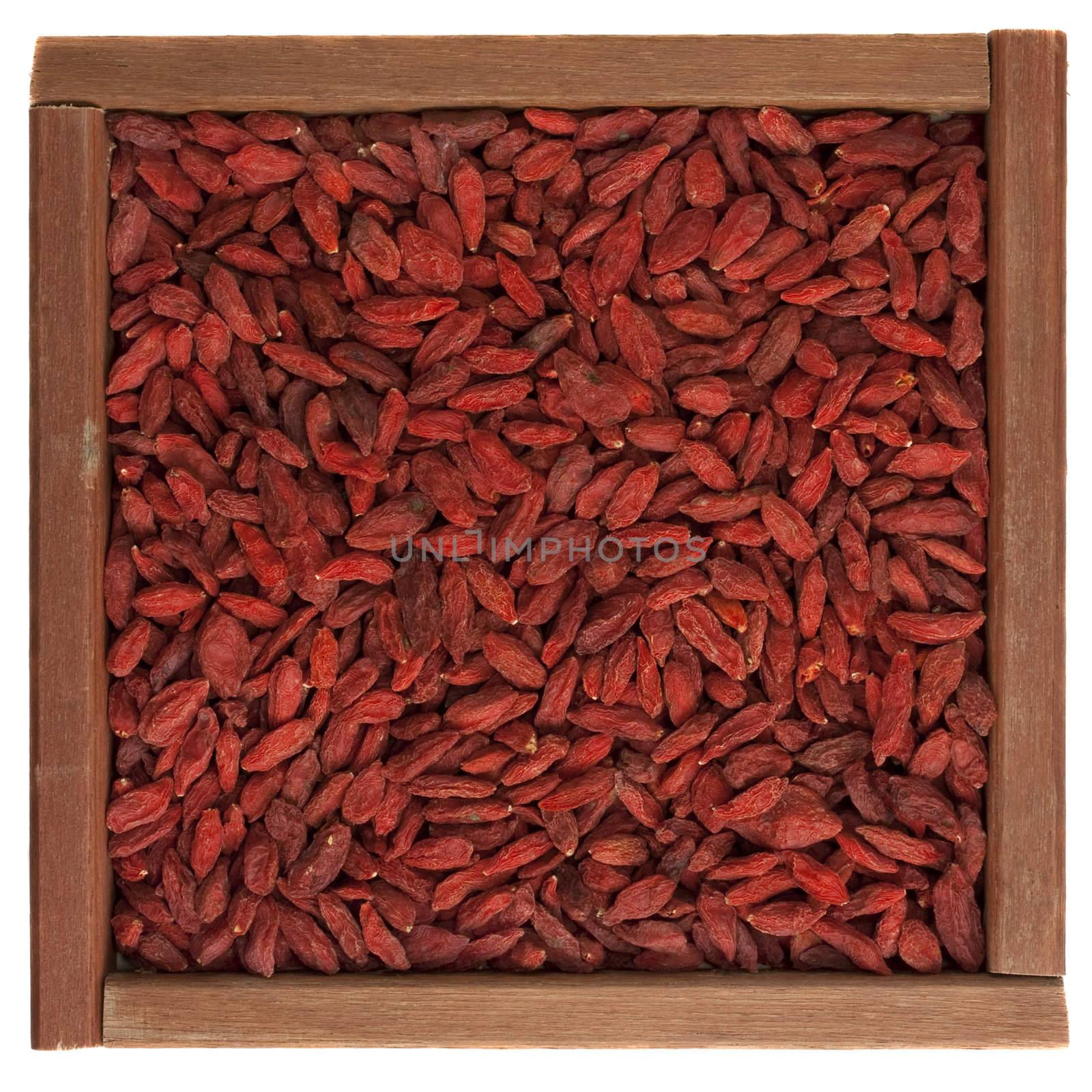 dried Tibetan goji berries (wolfberry) in a rustic wooden box isolated on white