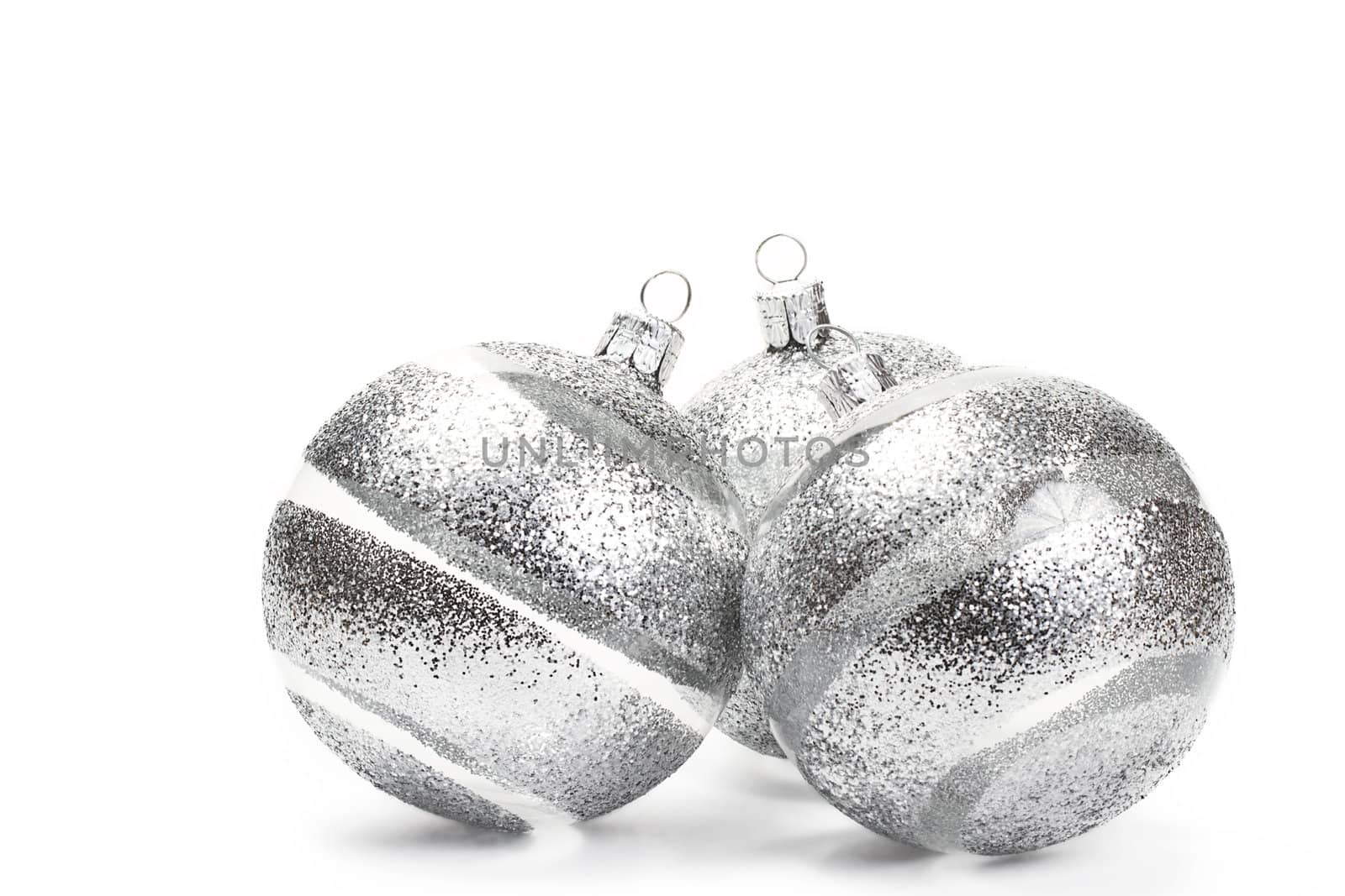 three clear christmas balls with glitter stripes on white background