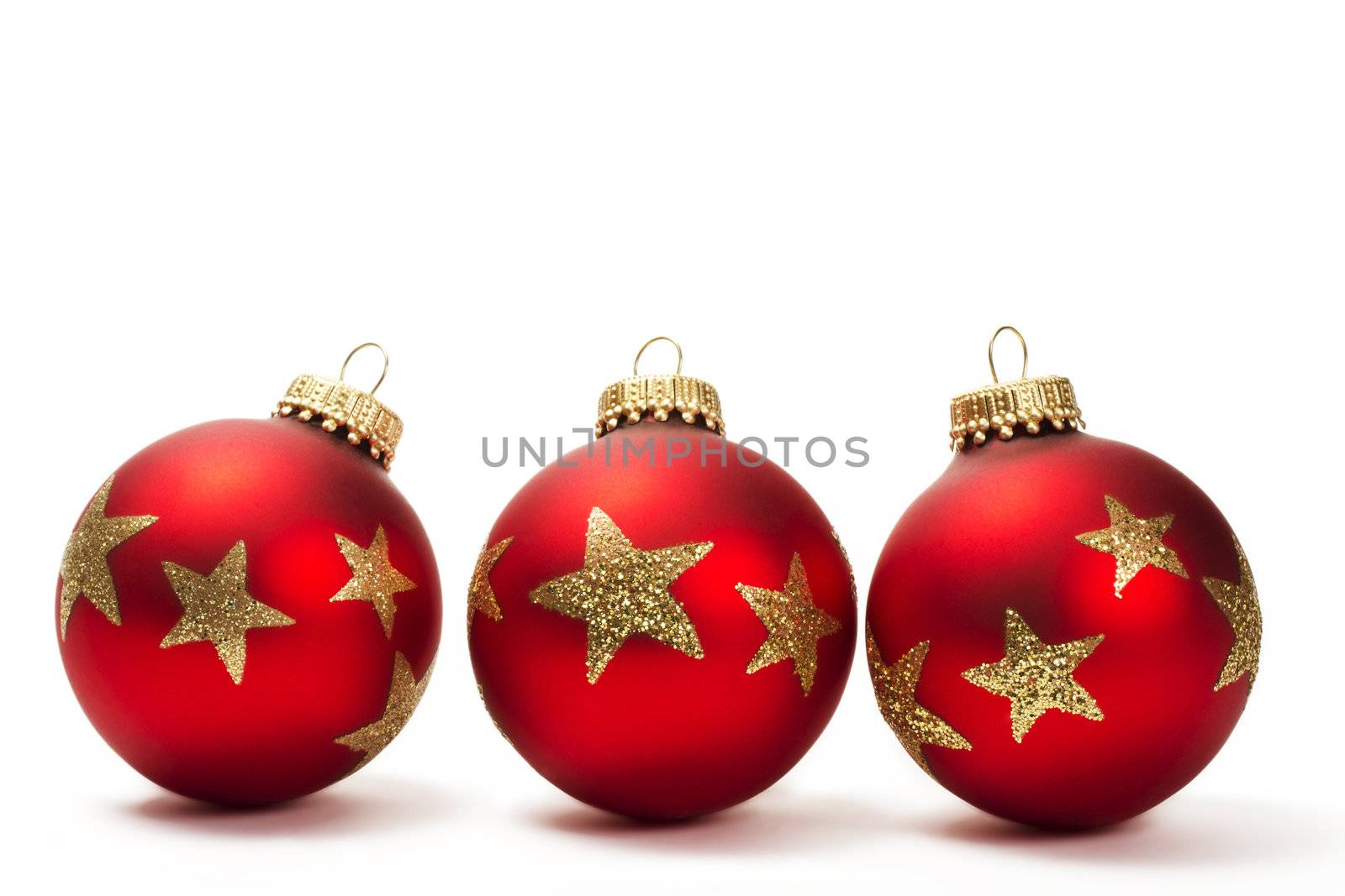 three red dull christmas balls with golden glitter stars on white background