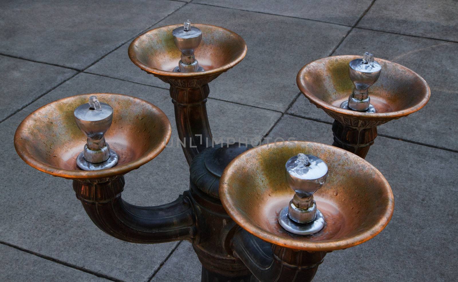 Old Four fountain City Water Bubbler  against grey sidewalk
