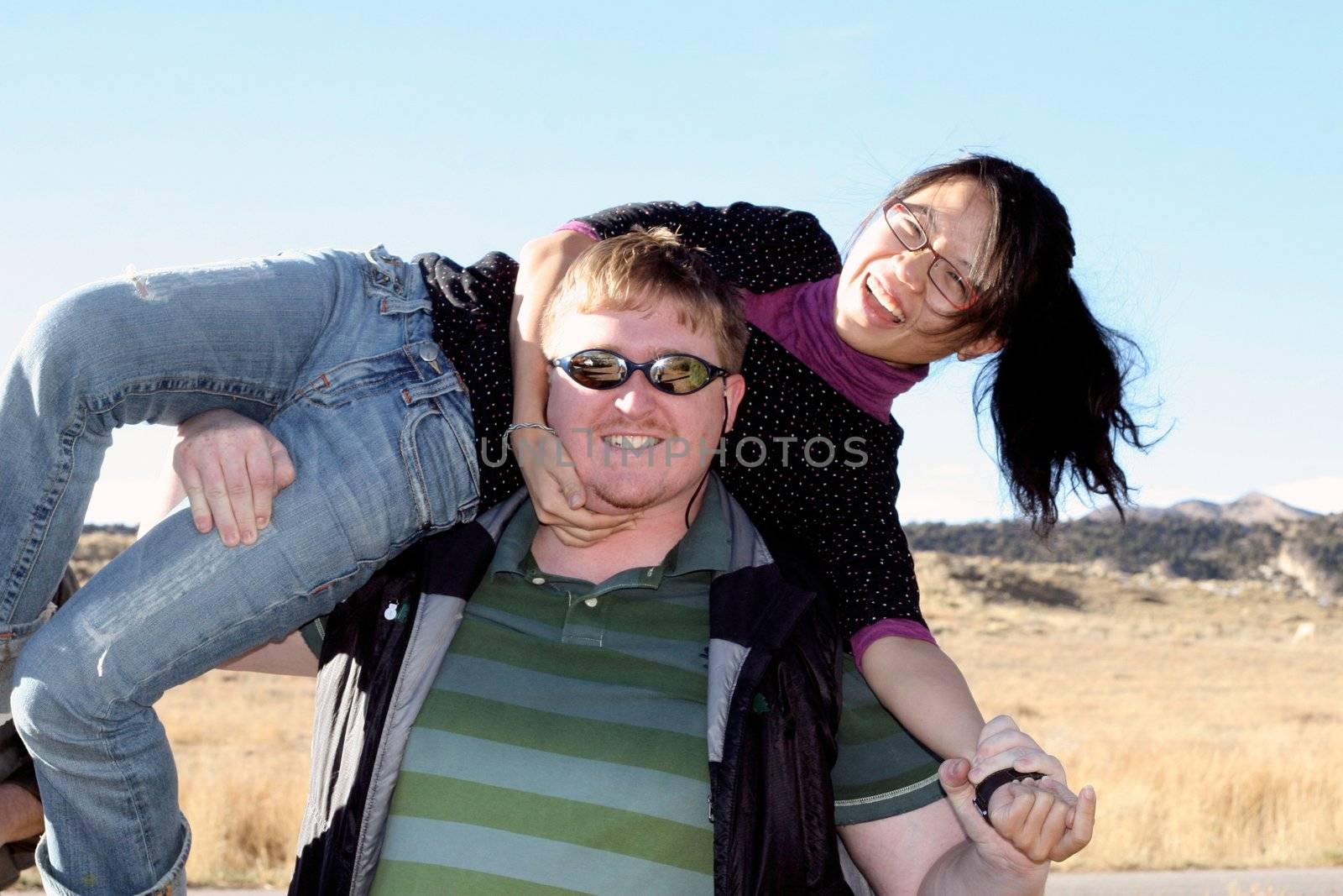 Young blonde man and beautiful asian woman having fun outdoors.