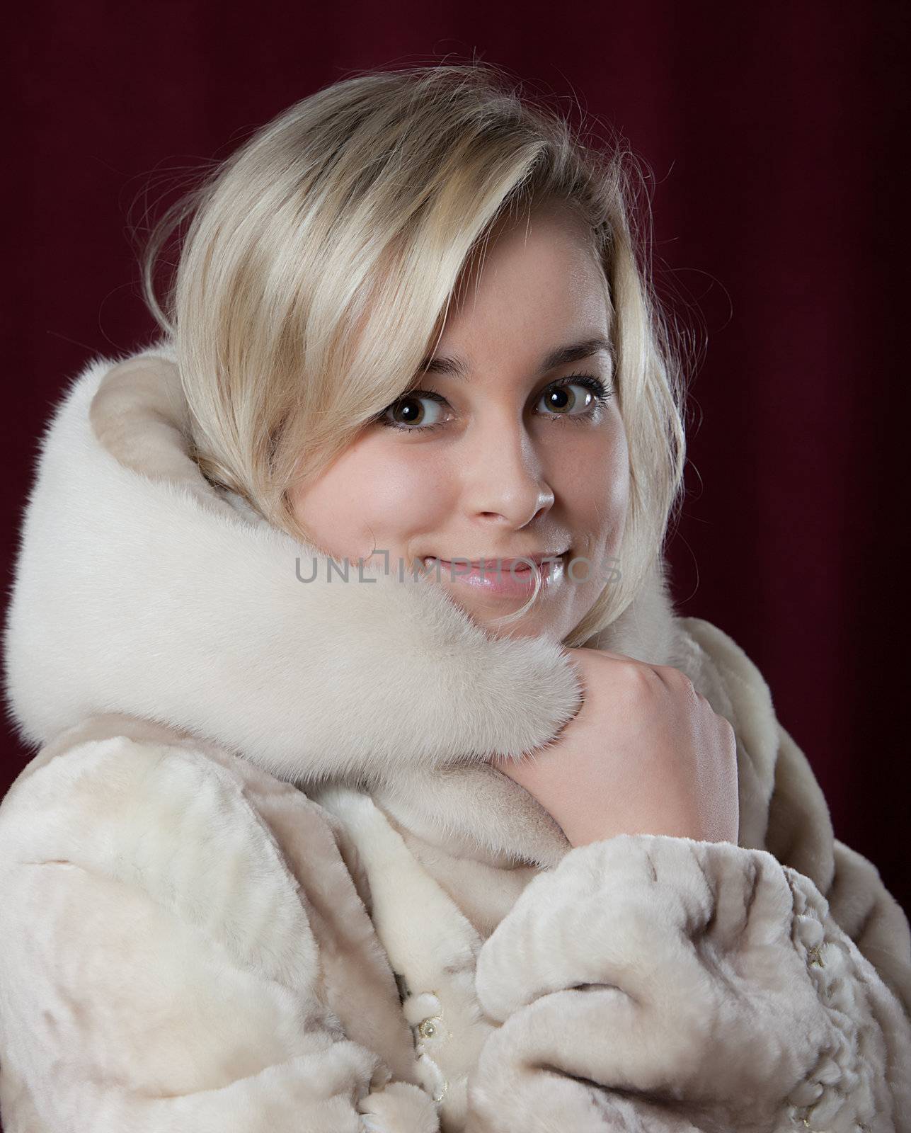 Portrait of the young beautiful girl in a fur coat on a dark background