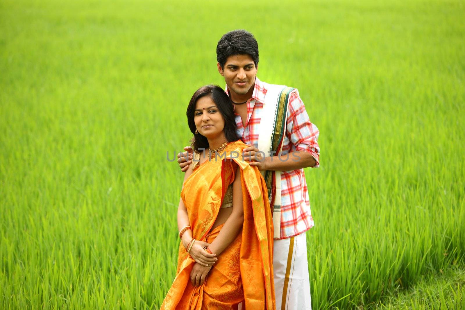 an asian couple standing in a paddy field