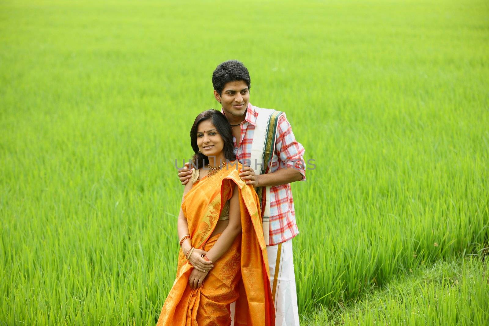 
an asian couple standing in a paddy field