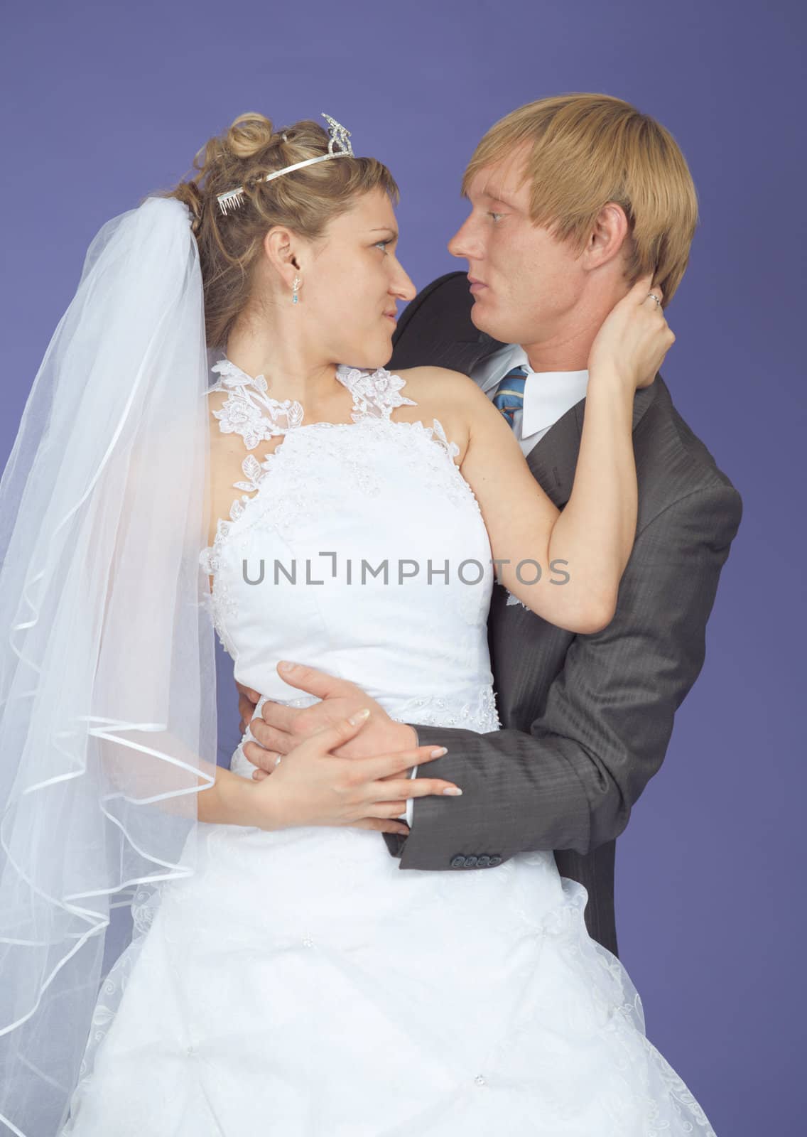 Romantic groom and the bride pose on a lilac background