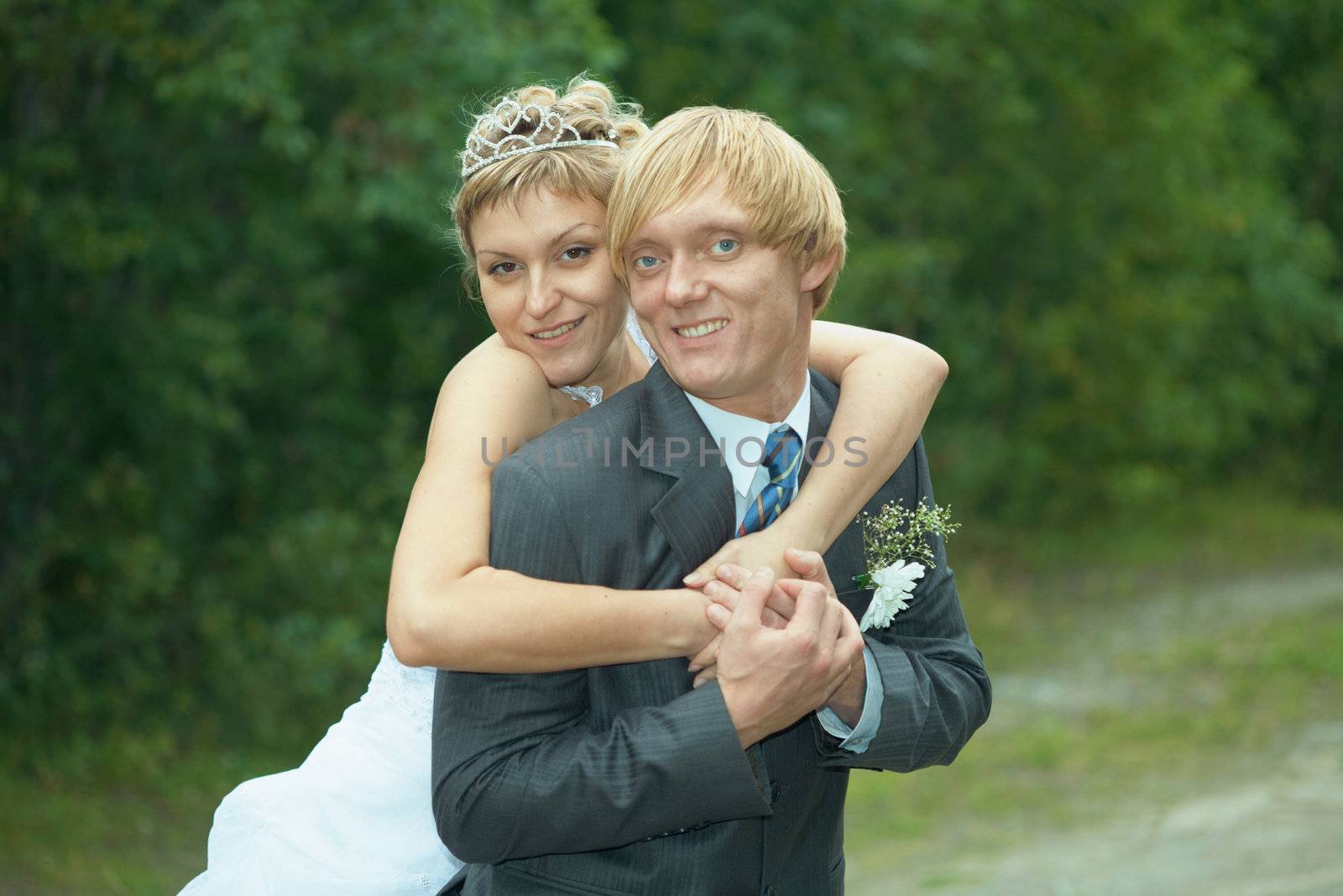 The smiling happy bride embraces the groom