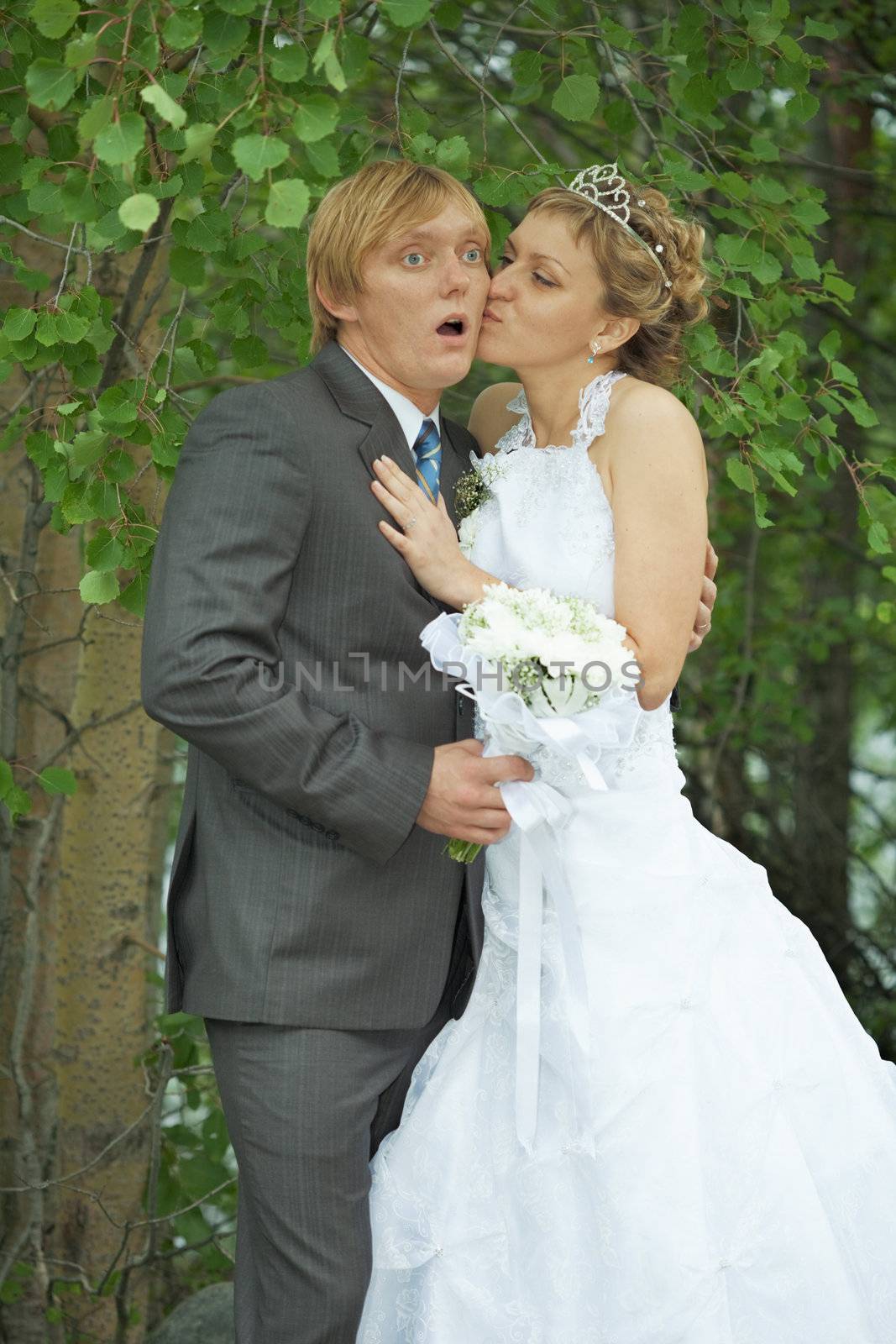 Amusing groom and the bride kiss secretly in bushes
