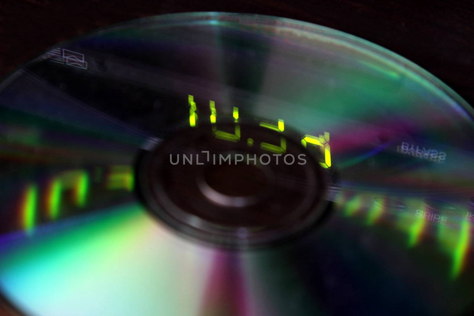 A closeup of dvd with the lights from a digital display reflecting on them.  Note the focus is on the digits.