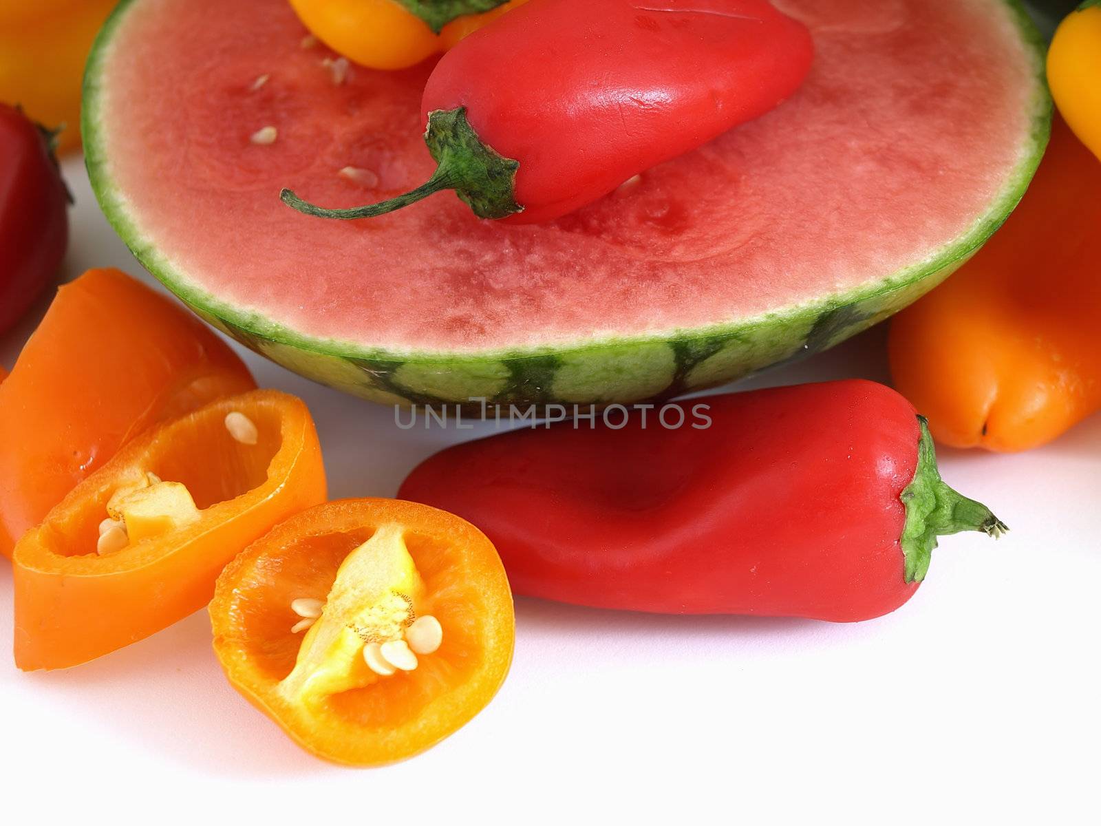 A vibrant summer crop of fresh juicy watermelon and colorful bell peppers, studio isolated over a white background.