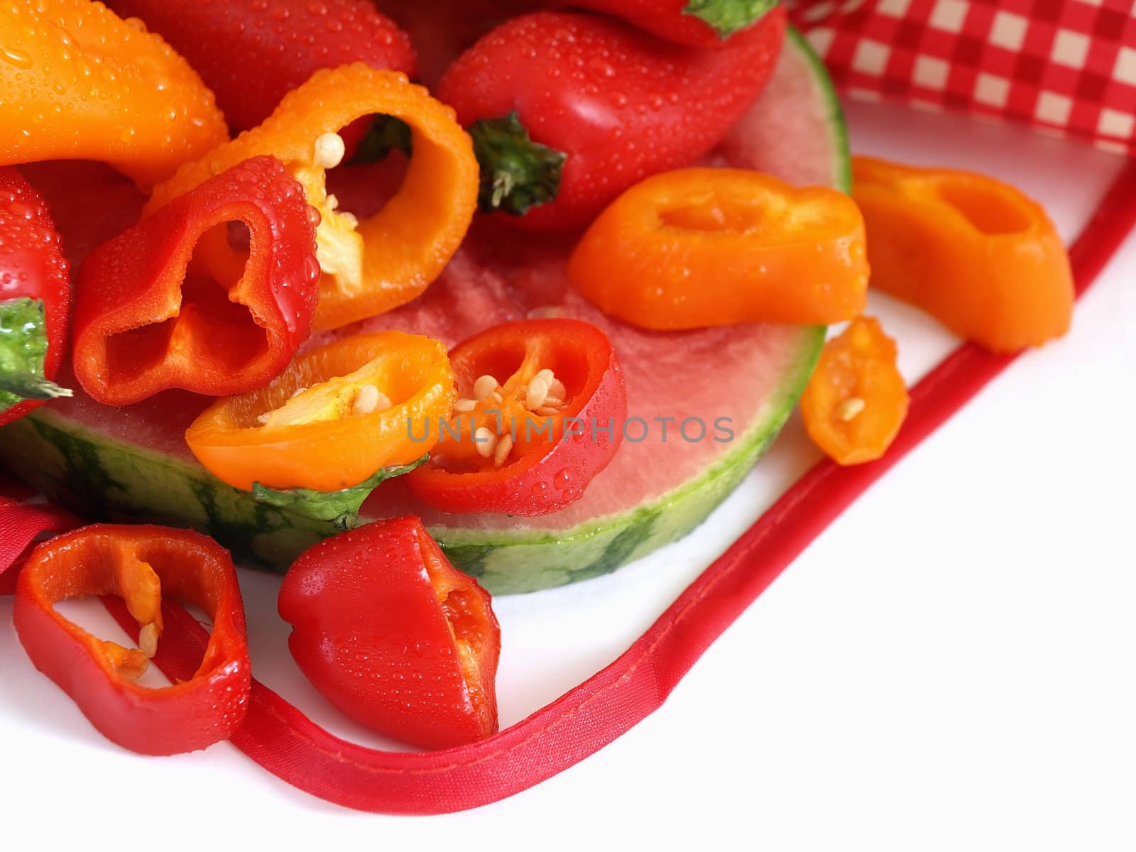 A vibrant summer crop of fresh juicy watermelon and colorful bell peppers, studio isolated over a white background.