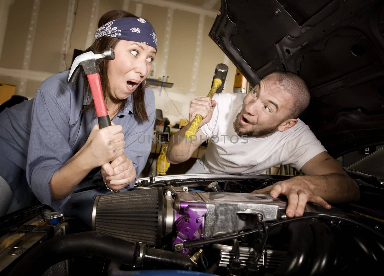 Hapless mechanics working on car engine with hammers