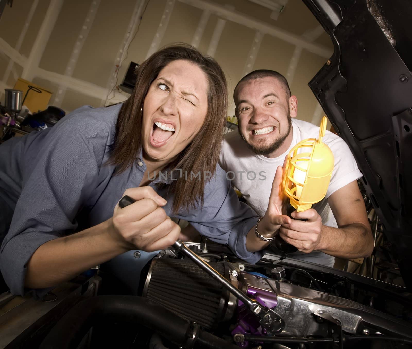 Hapless mechanics working on car engine getting in each others way