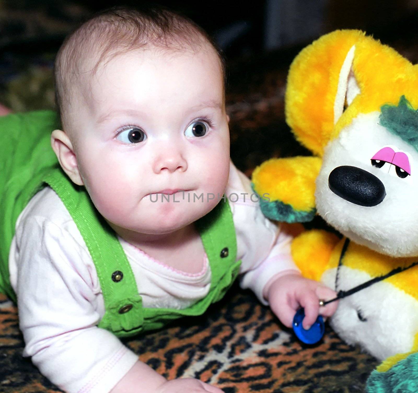 Pronating infant with yellow chinchilla toy looks at something