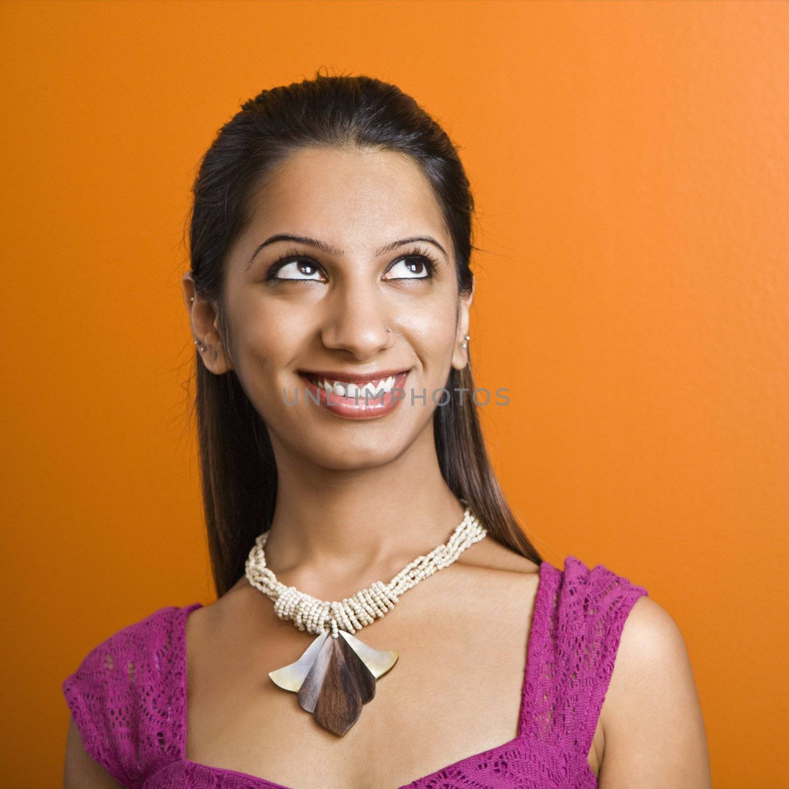 Attractive young adult Indian woman smiling at looking up.
