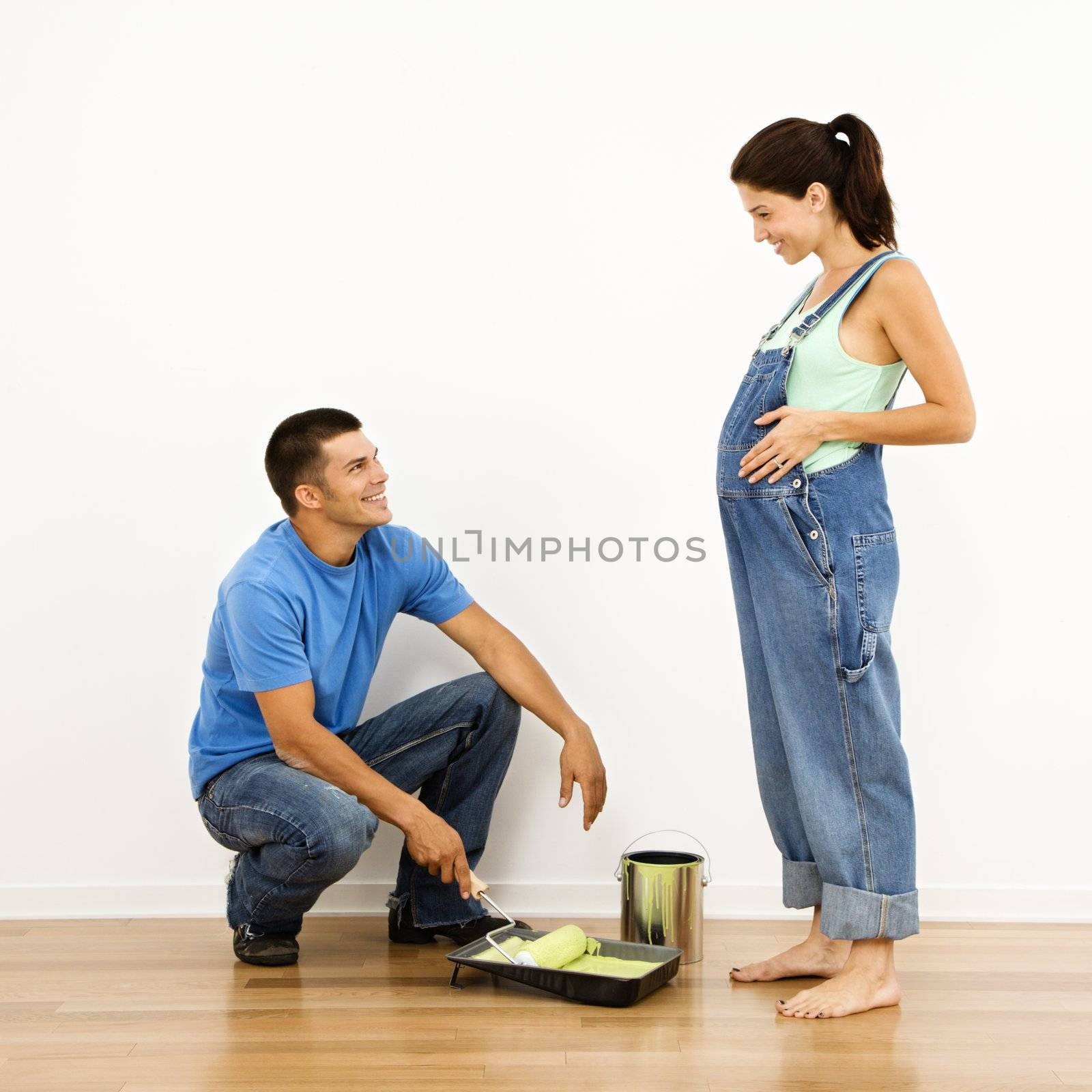 Pregnant woman and husband preparing to paint interior home wall.