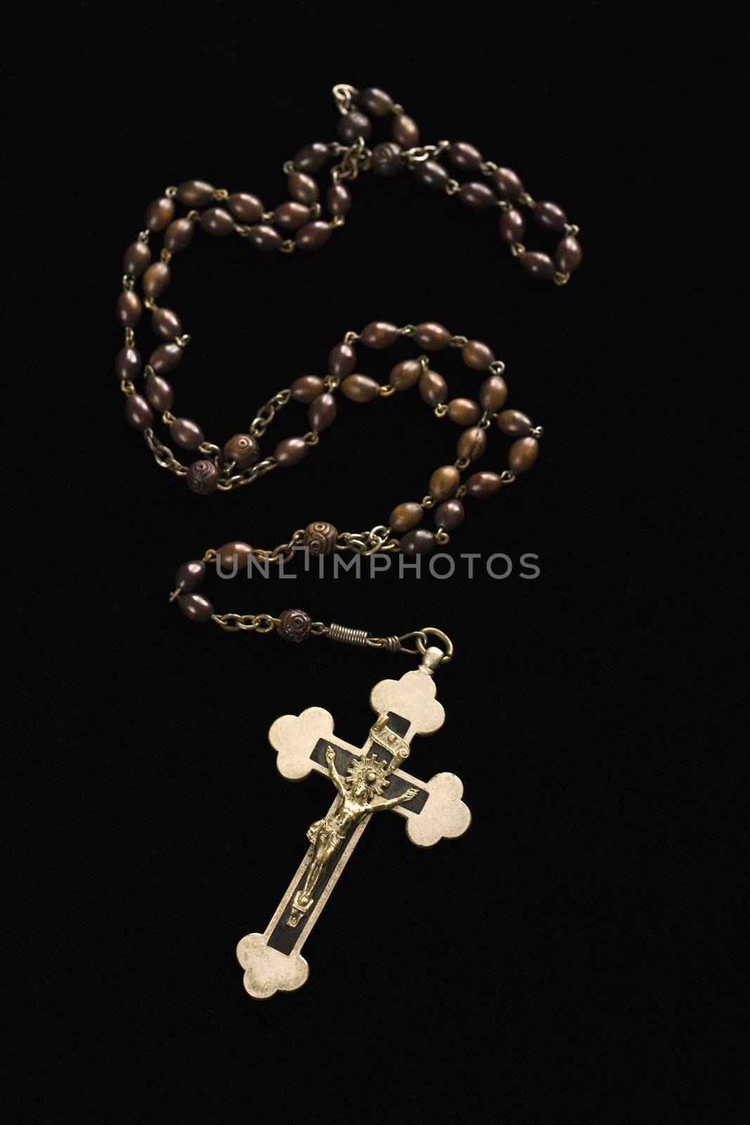 Christian rosary beads with crucifix on black background.