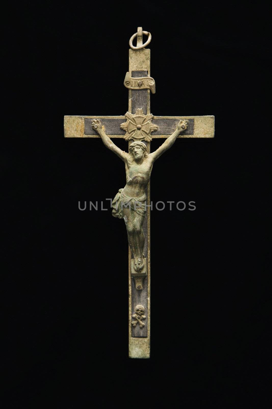 Crucifix religious Christian pendant against black background.