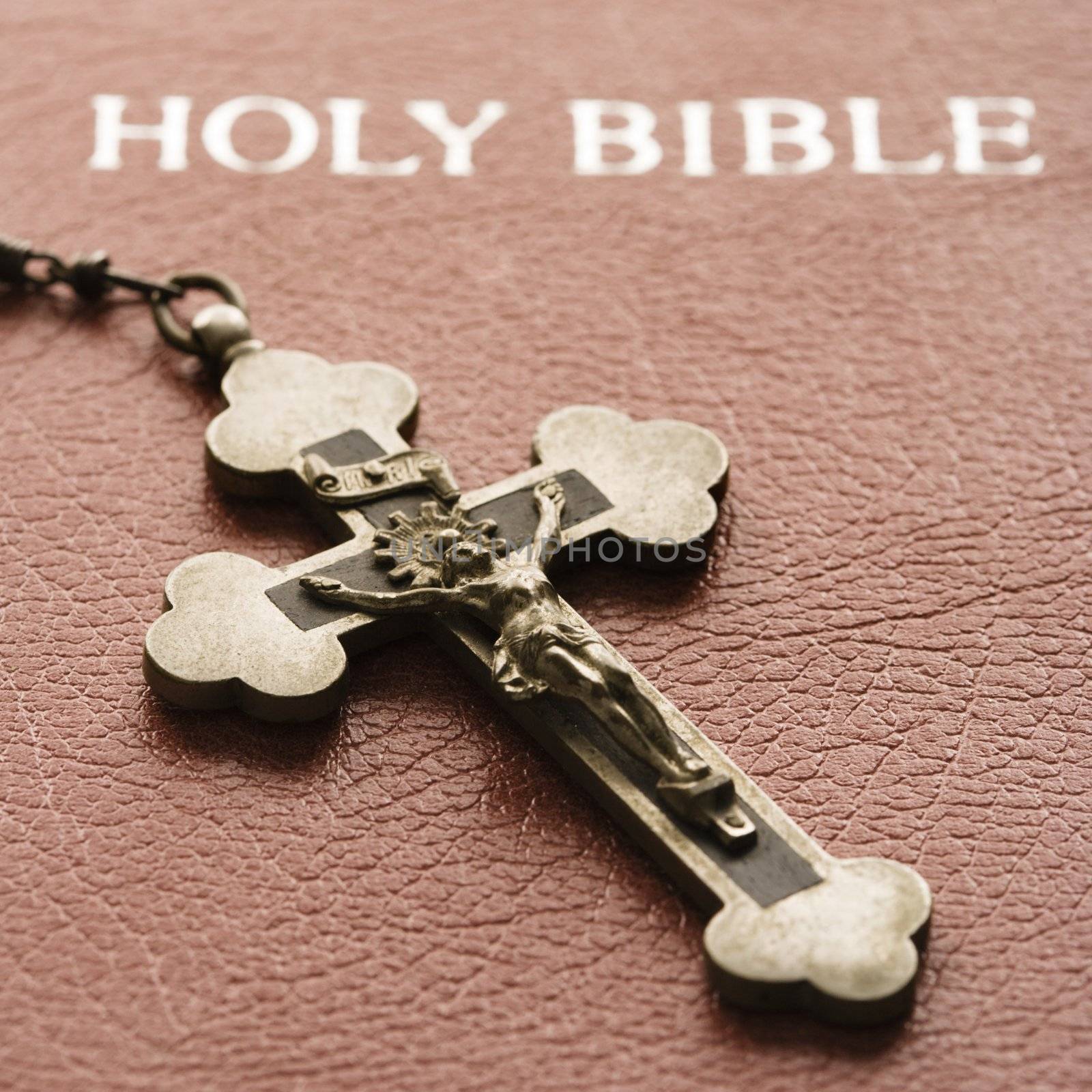 Crucifix lying on cover of closed Holy Bible.