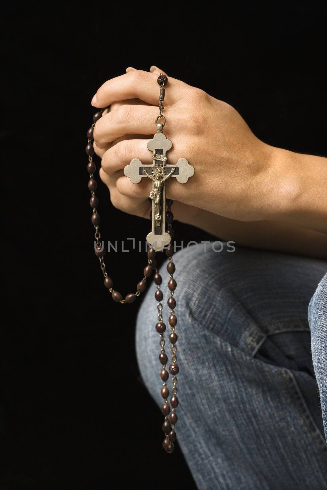 Woman's hands holding rosary with crucifix.