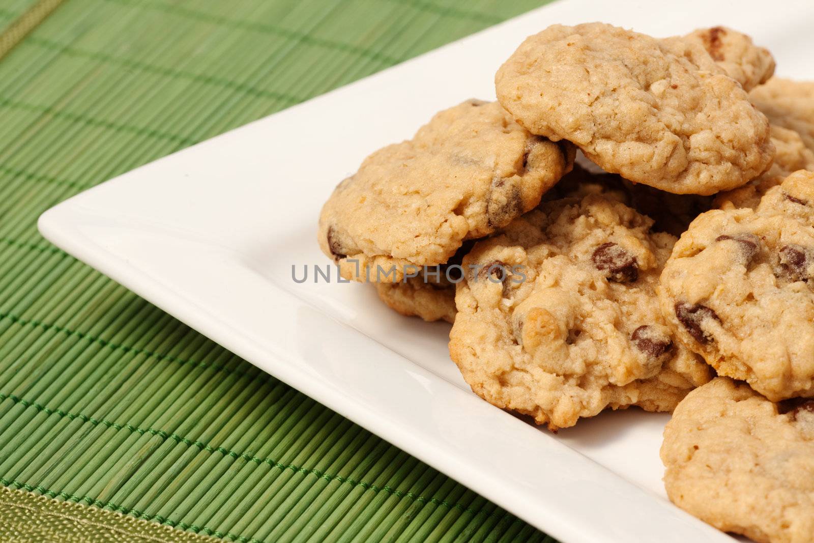 A plate of oatmeal chocolate chip cookies on a green mat
