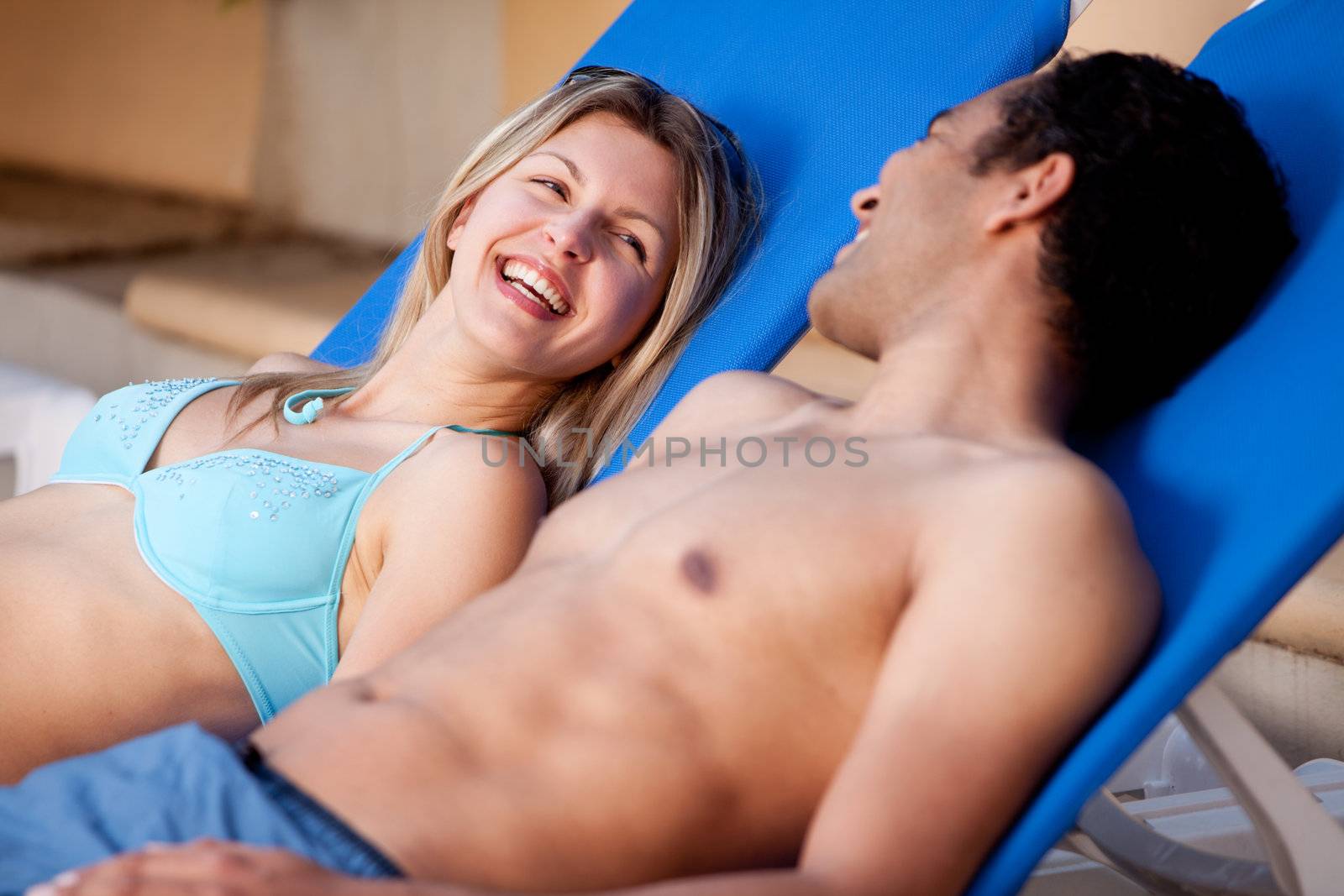 A happy couple on pool side chairs having fun